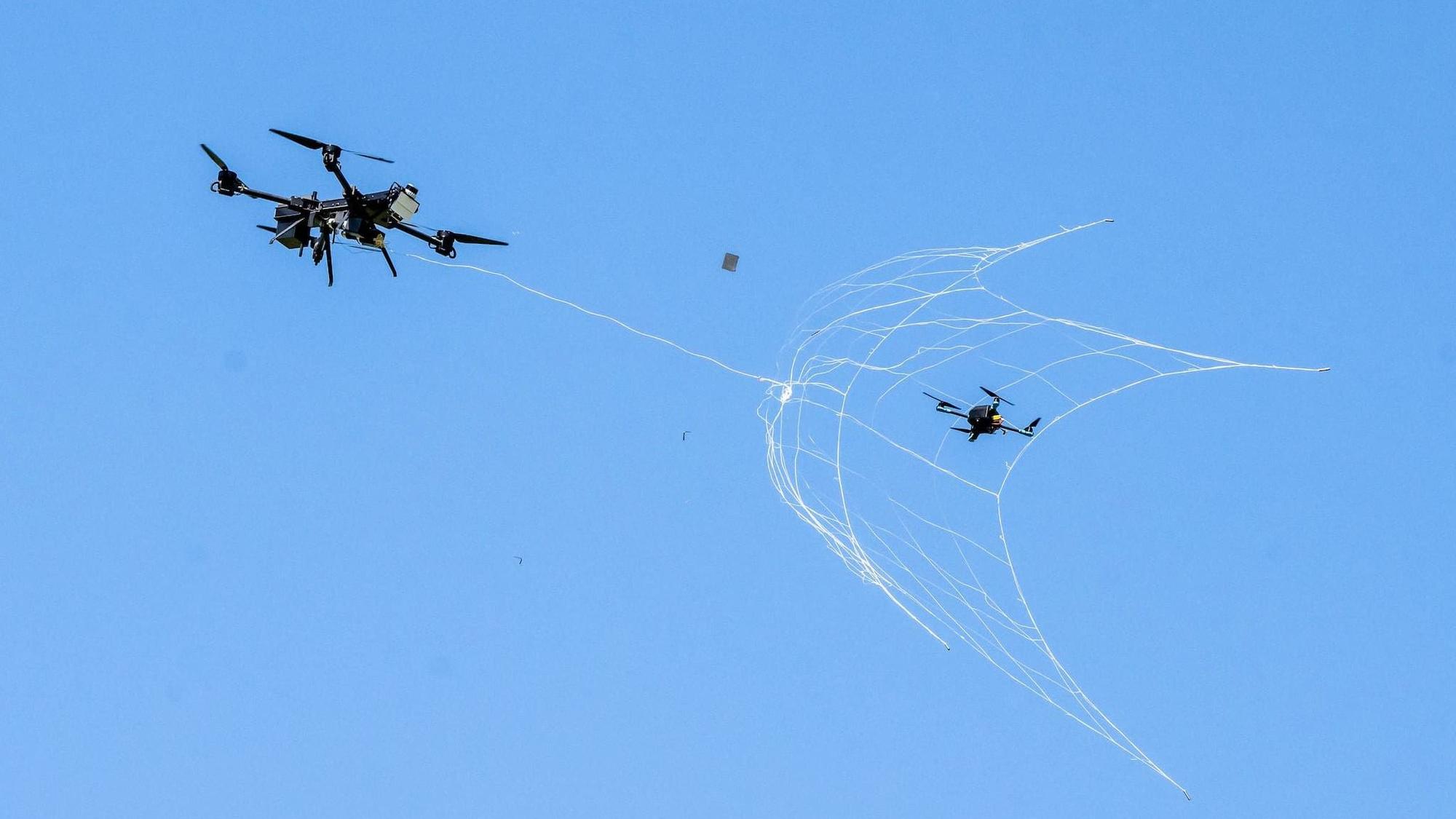 Eine Drohne fängt eine kleine Drohne mit einem Netz.