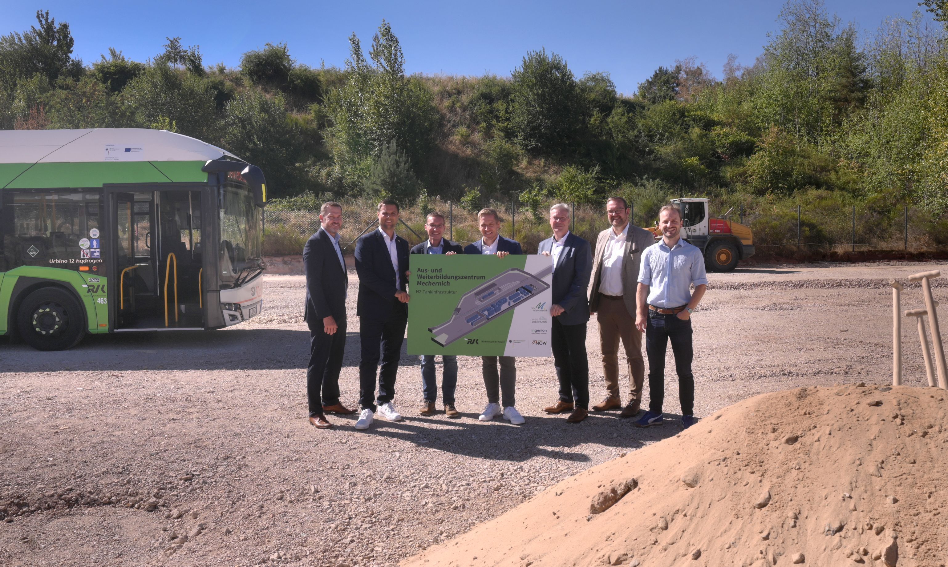 Neben einem Bus stehen (v.l.) Heiko Iffland (Geschäftsführer Ingenion), Michael Fingel (Bürgermeister Stadt Mechernich), Dr. Marcel Frank (Geschäftsführer RVK), Markus Ramers (Landrat Kreis Euskirchen), Achim Blindert (Allg. Vertreter des Landrates Kreis Euskirchen), Thomas Hambach (Beigeordneter, Stadt Mechernich), Matthias Mohr (Anlagentechnik, RVK) und halten gemeinsam ein Plakat.