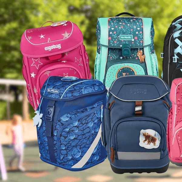 Sechs verschiedene Schulrucksäcke und Schulranzen bekannter Marken vor einem unscharfen Schulhof-Hintergrund: ein pinker Ergobag-Ranzen mit Sternenmotiv, ein türkiser McNeill-Schulranzen mit Blumen- und Rehmotiv, ein schwarzer Coocazoo-Rucksack mit geometrischem Muster, ein blauer Herlitz-Schulranzen mit Blasenmuster, ein blaugrauer Ergobag-Ranzen mit Bärenmotiv sowie ein dunkelroter Step-by-Step-Ranzen mit Sternenmuster.