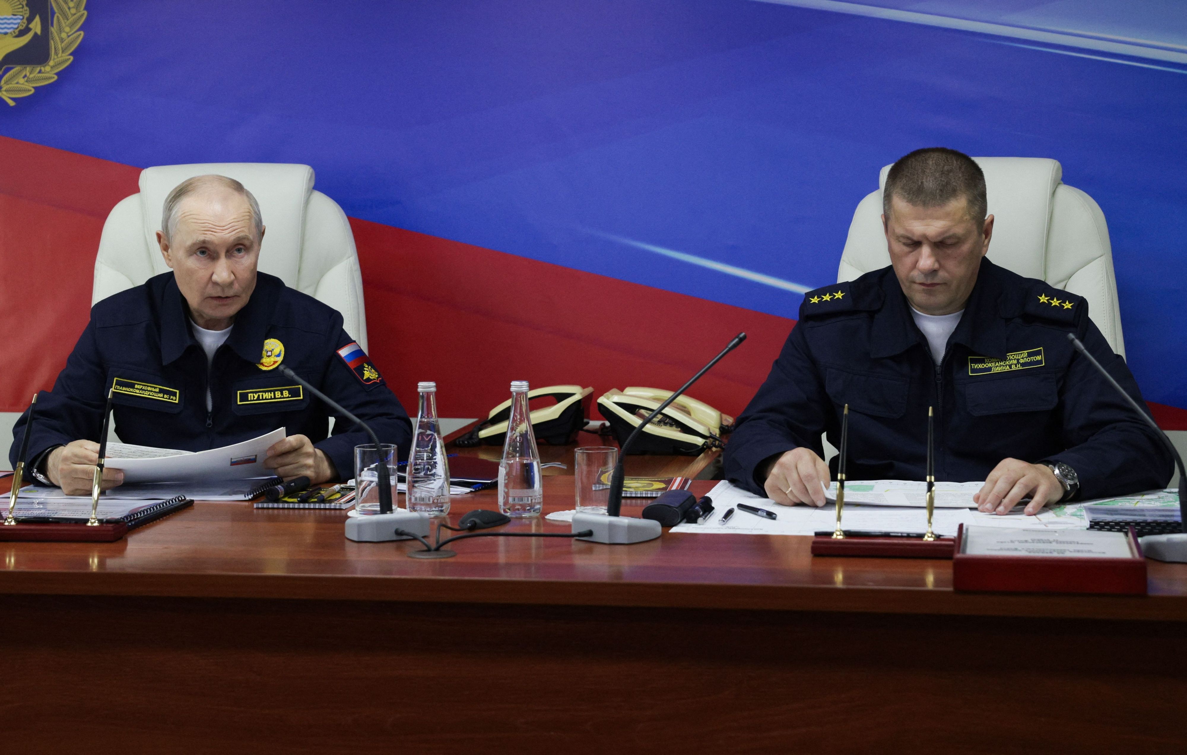 Auf diesem von der russischen Staatsagentur Sputnik verbreiteten Pool-Foto nehmen der russische Präsident Wladimir Putin und der Kommandeur der russischen Pazifikflotte, Admiral Viktor Liina, am 12. August 2026 während der Abschlussphase eines Manövers der Pazifikflotte auf der russischen Insel Sachalin an Bord des Lenkwaffenkreuzers „Warjag“ an einer Besprechung teil.
