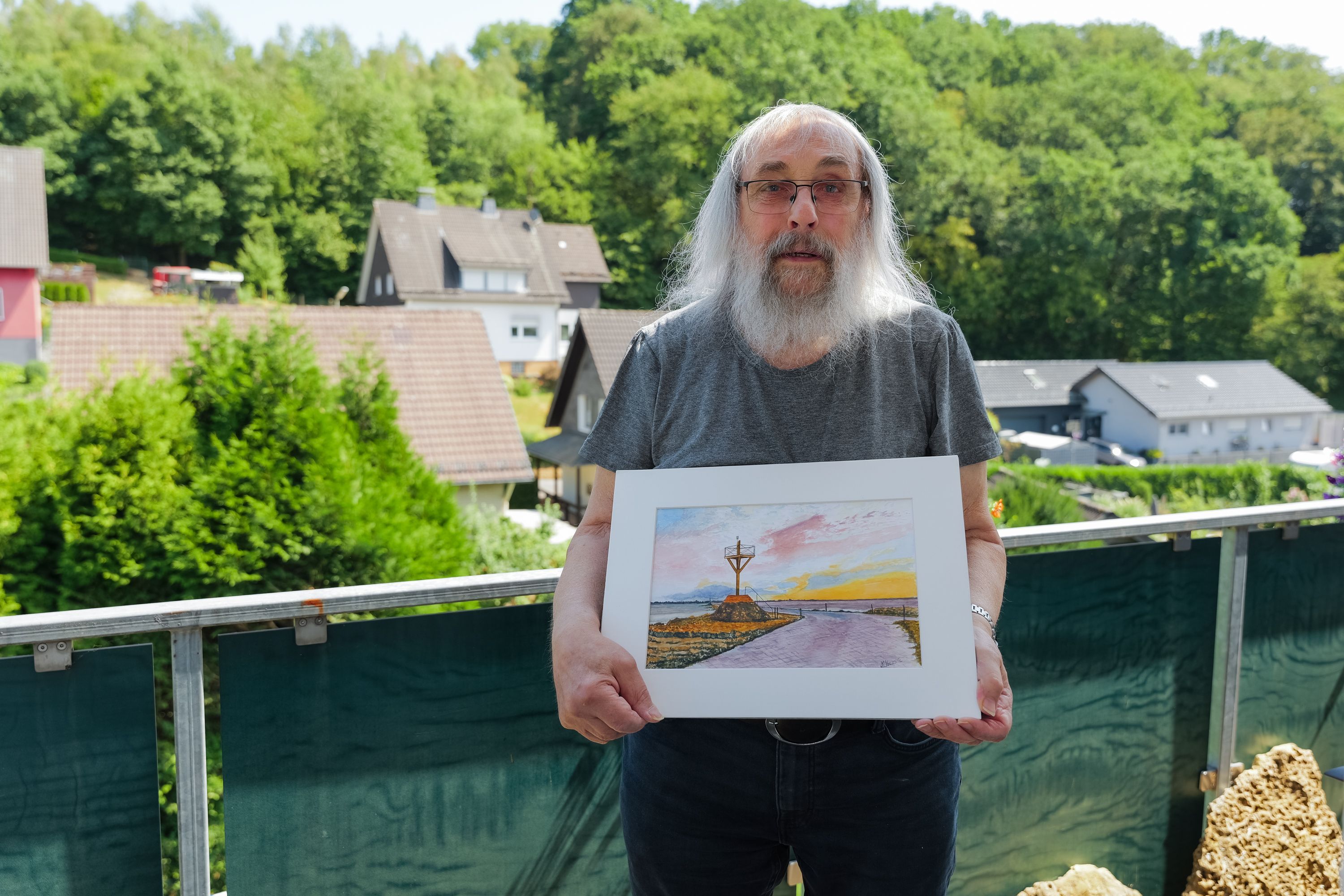 Georg Seifert aus Engelskirchen-Schnellenbach zeigt das Bild von Jean Marie Hermite aus La Roche-sur-Yon, auf dem die Passage du Gois zu sehen ist.