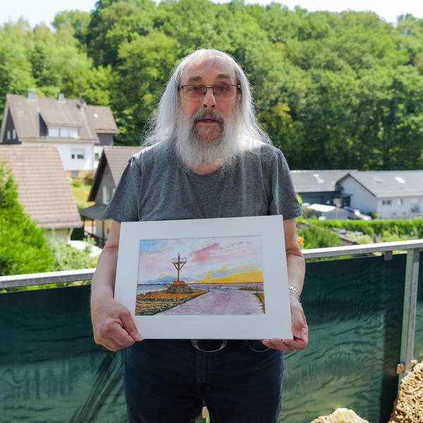 Georg Seifert aus Engelskirchen-Schnellenbach zeigt das Bild von Jean Marie Hermite aus La Roche-sur-Yon, auf dem die Passage du Gois zu sehen ist.