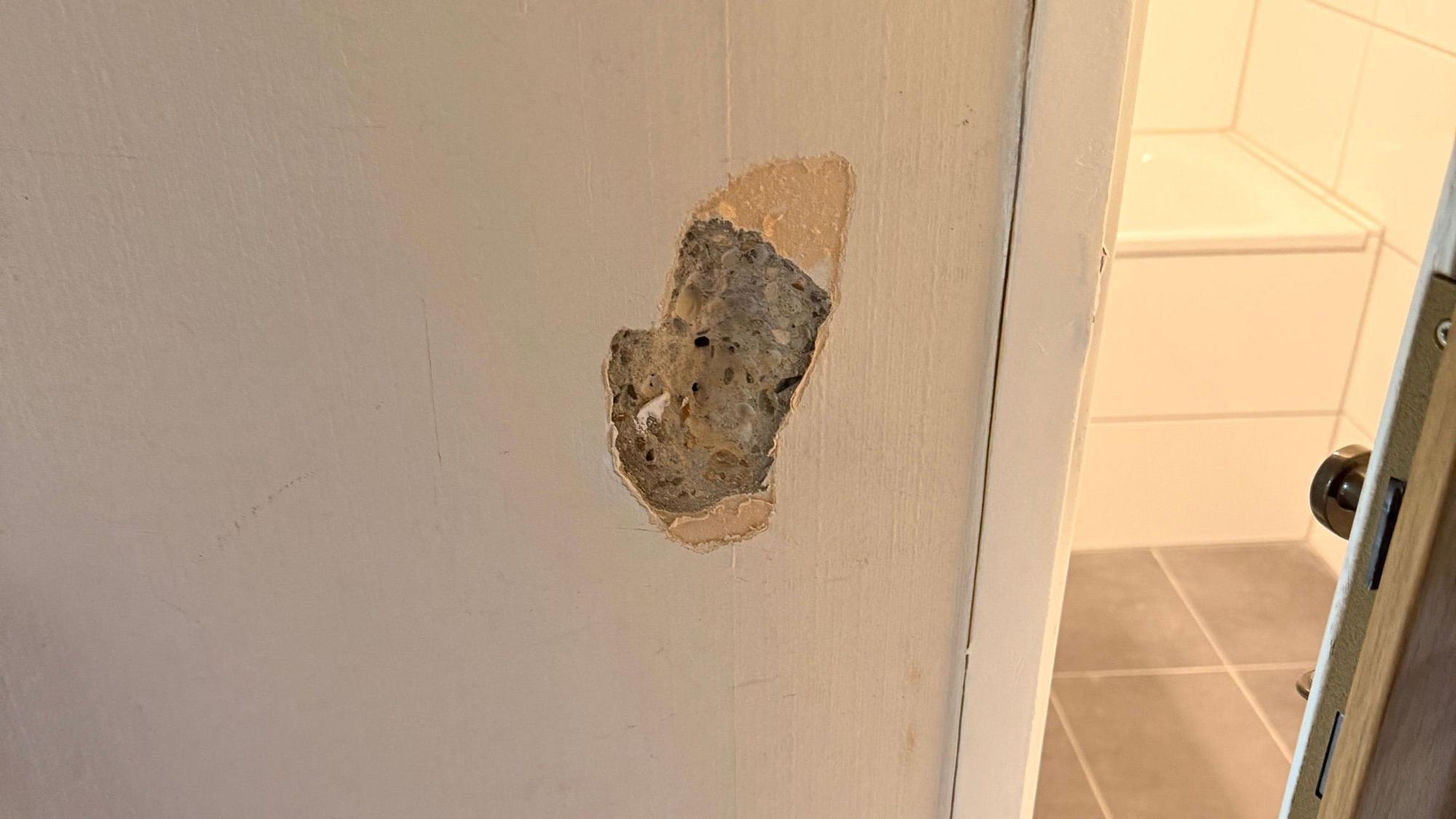 Ein faustgroßes Loch in einer verputzten Wand.