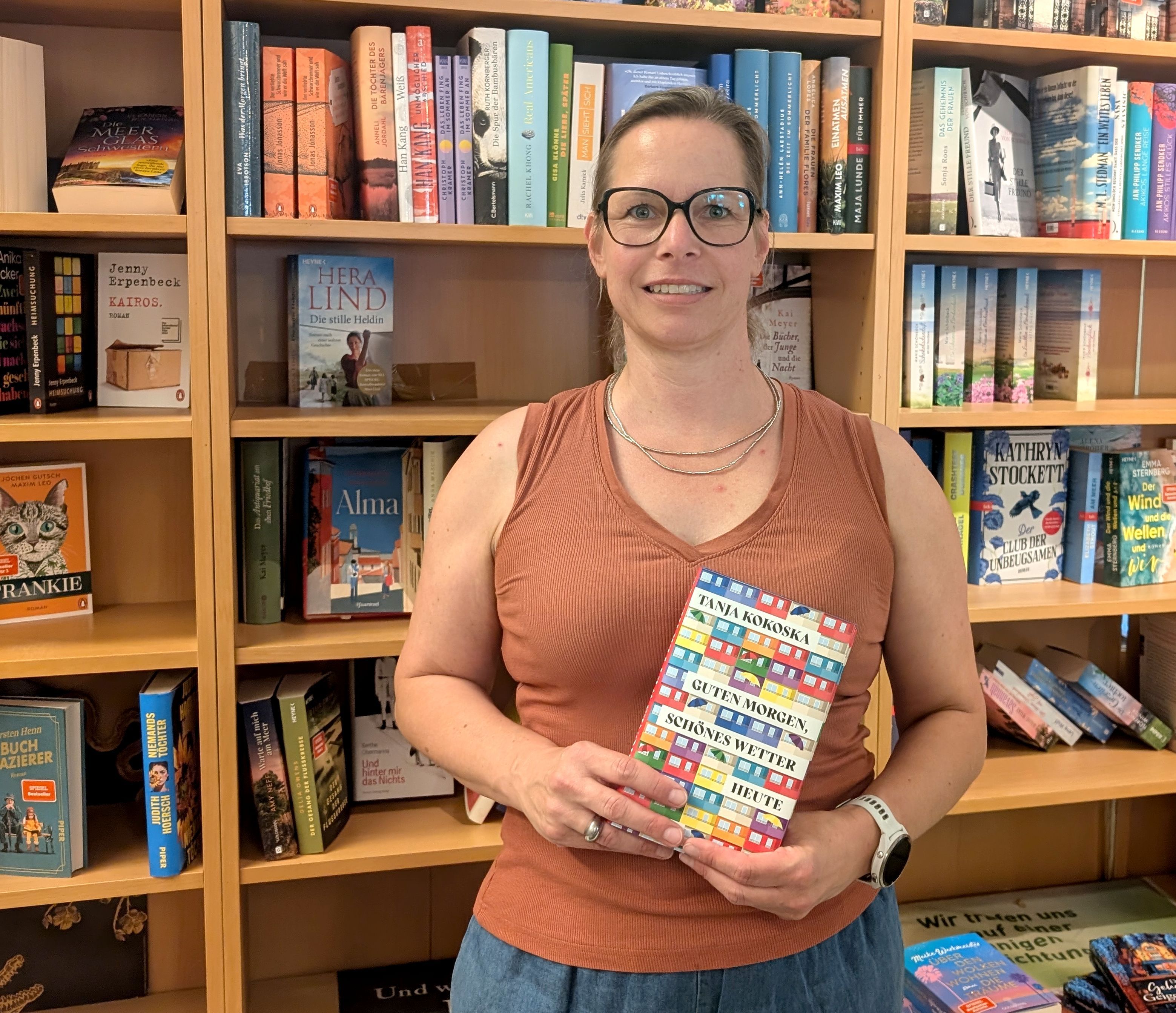 Buchhändlerin Stefanie Künstler steht mit einem Buch vor einem Bücherregal.