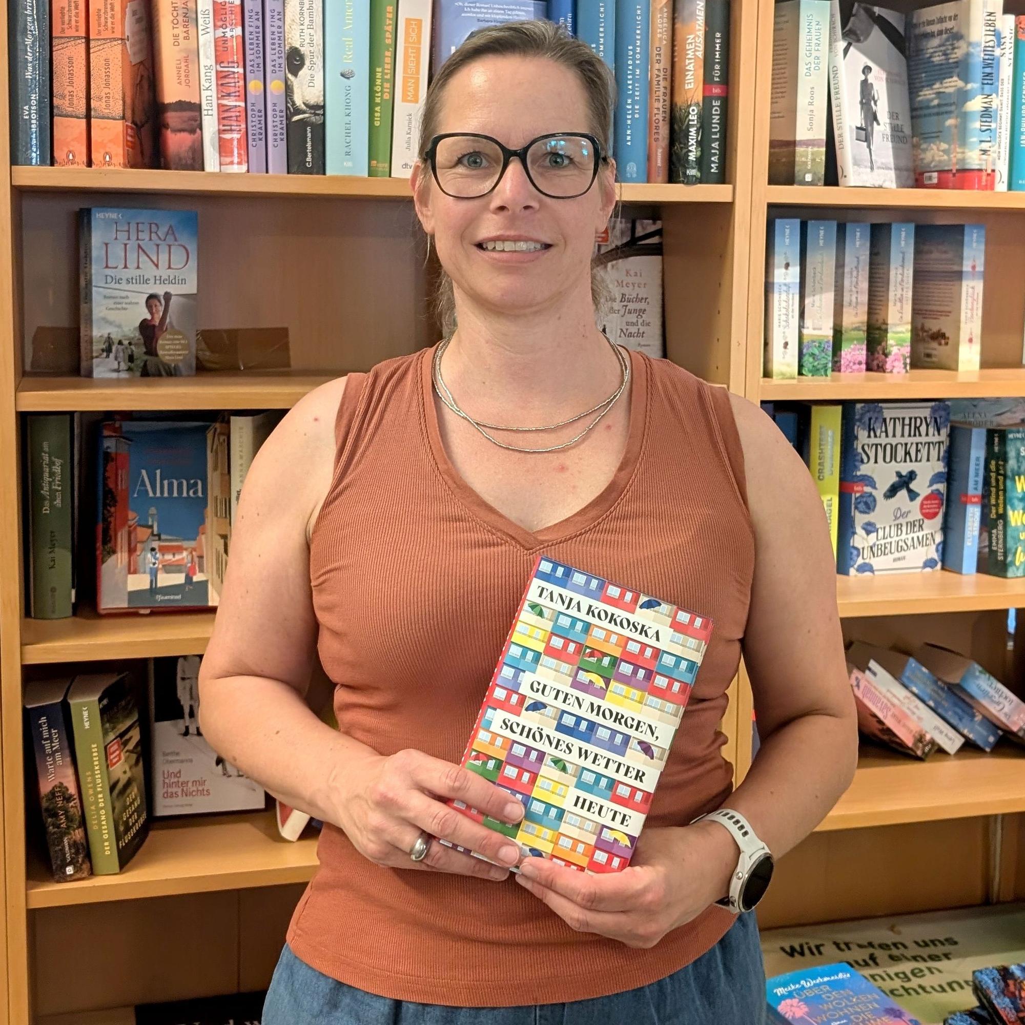 Buchhändlerin Stefanie Künstler steht mit einem Buch vor einem Bücherregal.