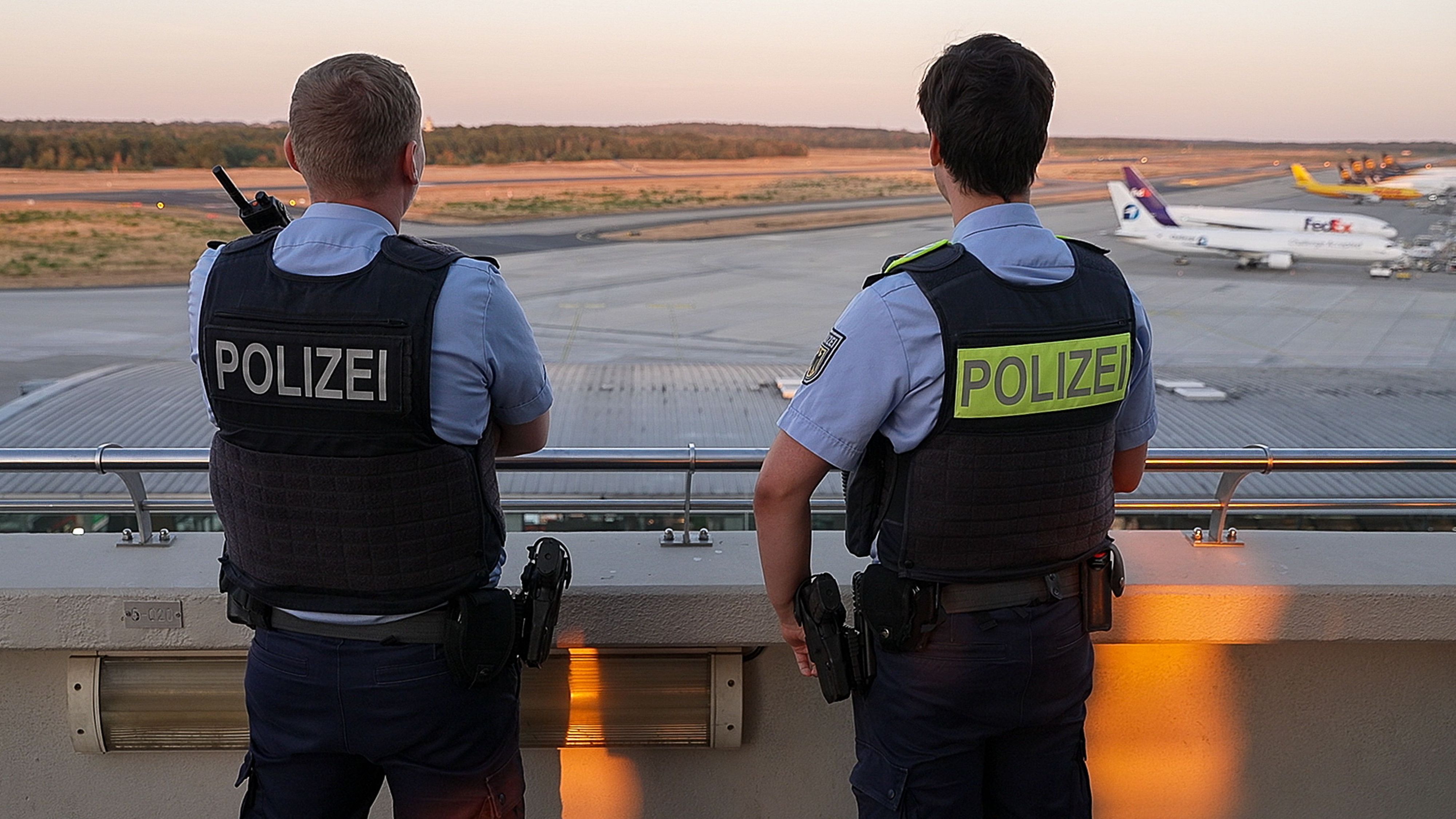 Einsatzkräfte der Polizei blicken auf das Gelände des Flughafens Köln/Bonn.