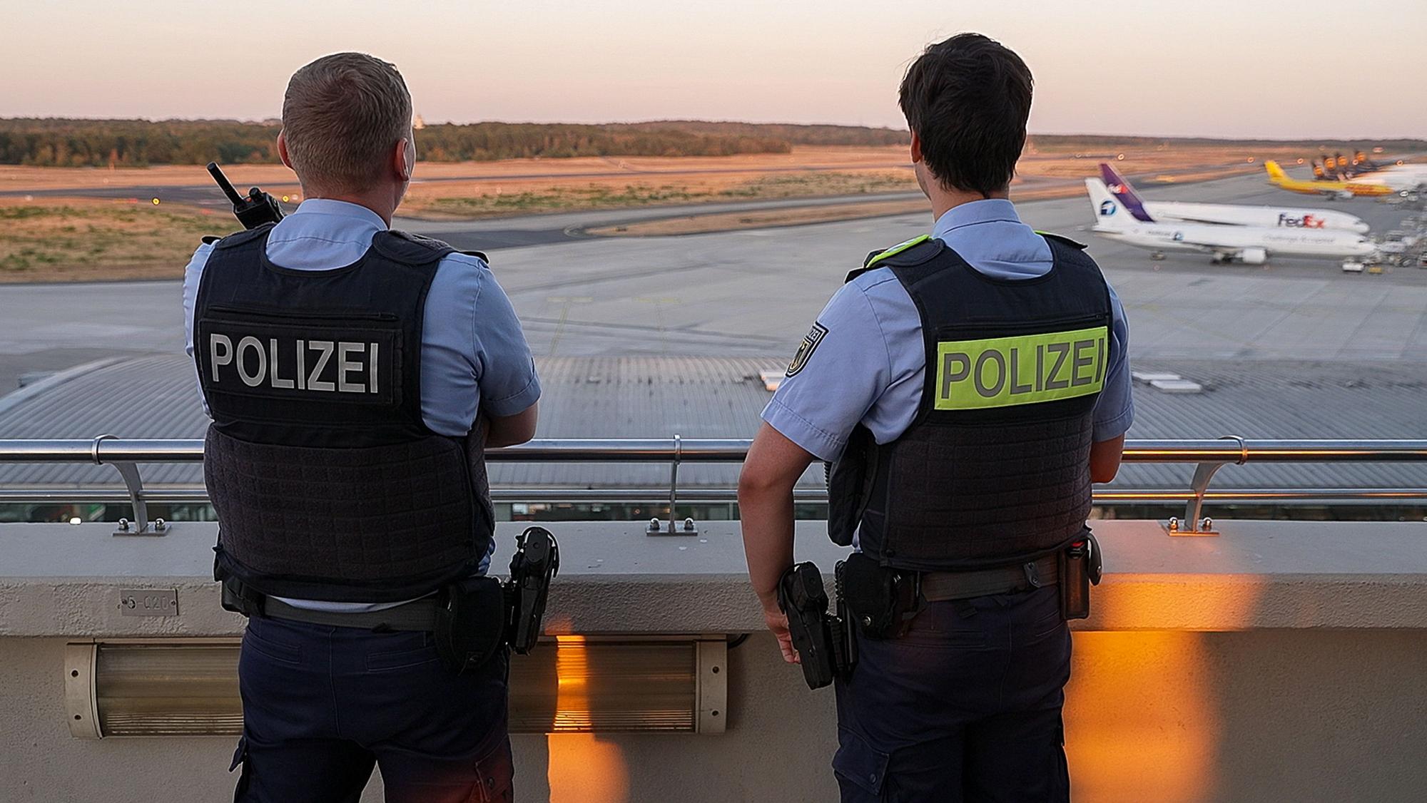 Einsatzkräfte der Polizei blicken auf das Gelände des Flughafens Köln/Bonn.