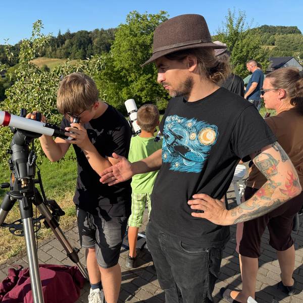 Ein Junge und ein Mann an einem Teleskop.