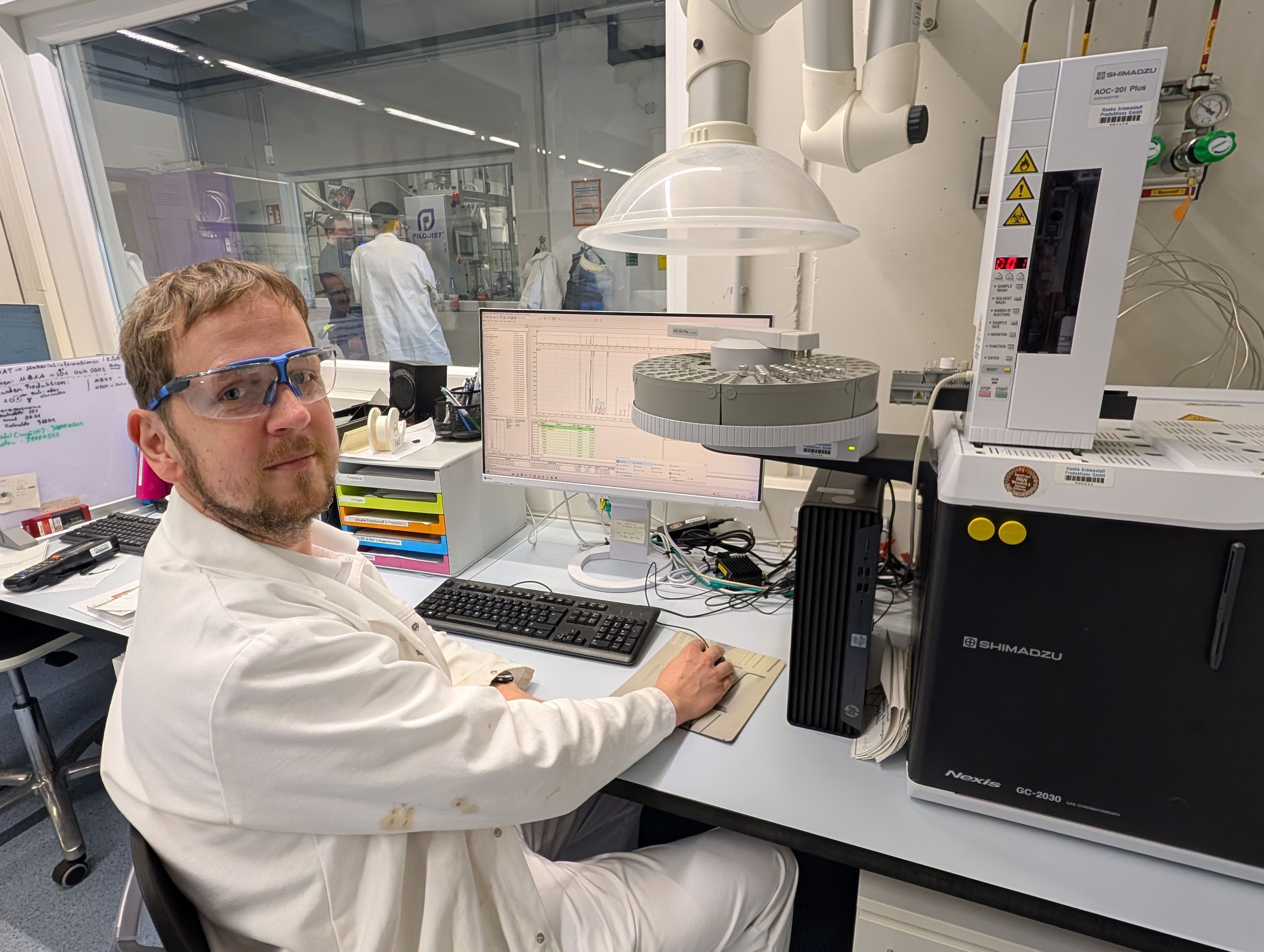 Das Foto zeigt den Chemiker vor dem Computer und einem Analysegerät.