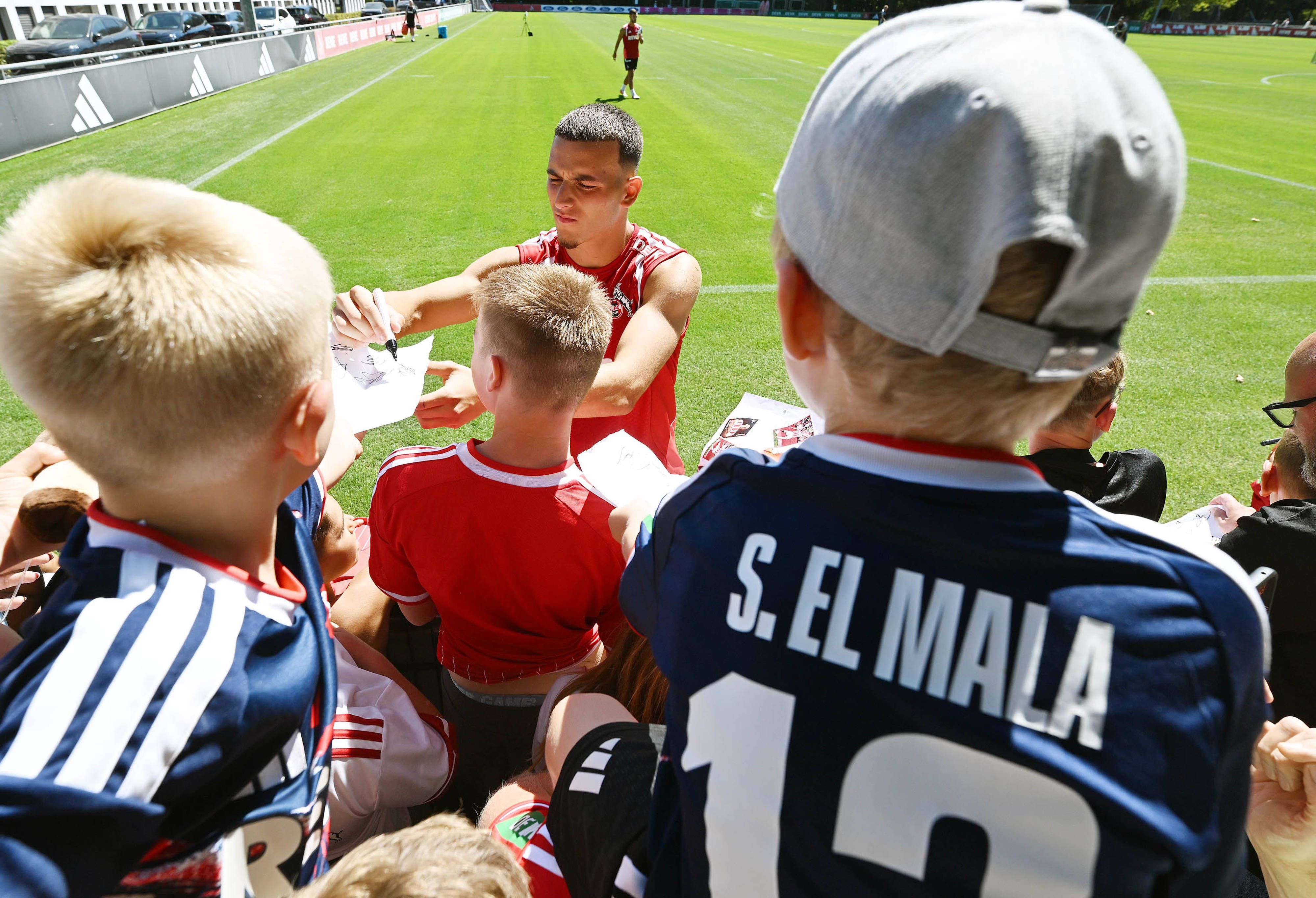Said El Mala schreibt Autogramme für junge FC-Fans beim Training.