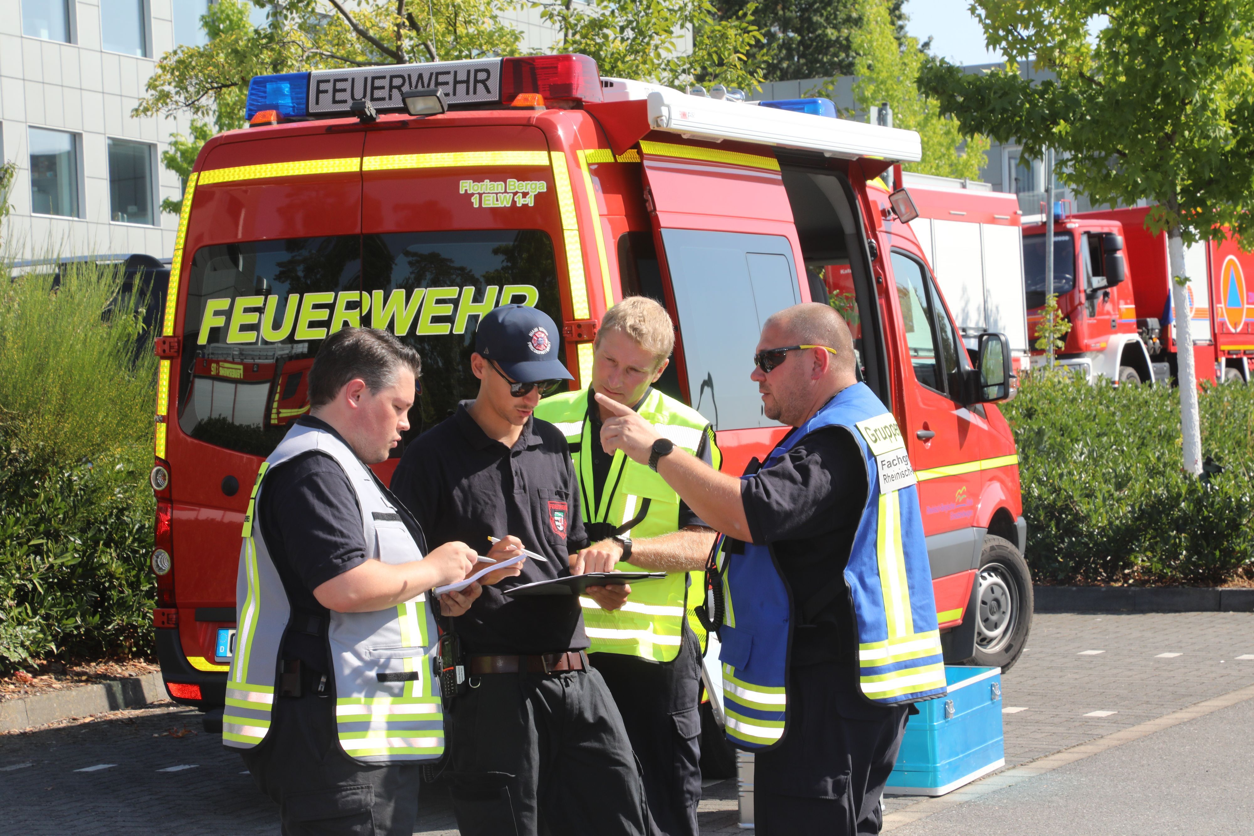Mehrere Führungskräfte der Feuerwehr stehen vor einem Einsatzleitfahrzeug am Kreishaus in Bergisch Gladbach-Heidkamp.