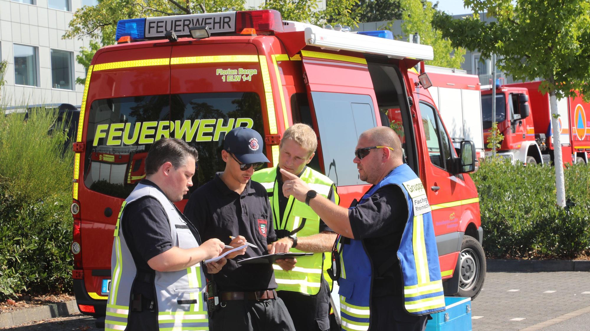 Mehrere Führungskräfte der Feuerwehr stehen vor einem Einsatzleitfahrzeug am Kreishaus in Bergisch Gladbach-Heidkamp.