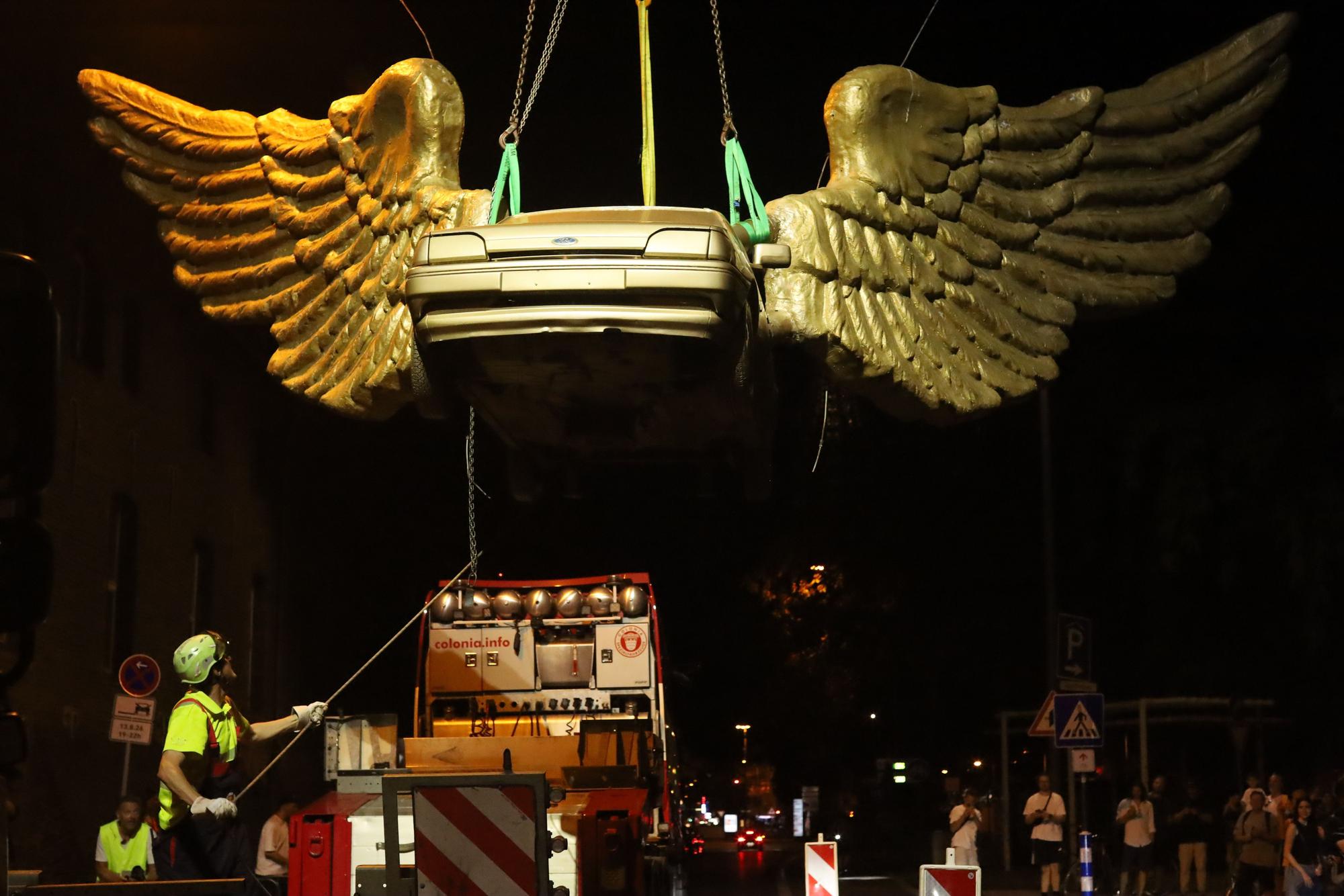 13.08.2026, Köln: Der „Goldene Vogel“, eine meist nur als „Flügelauto“ bezeichnete Skulptur des Künstlers HA Schult, wird von seinem Platz auf dem Treppenturm des historischen Zeughauses entfernt. Dort war es seit 1991 platziert. Nach einer Restauration soll es an anderer Stelle wieder aufgestellt werden. Foto: Arton Krasniqi