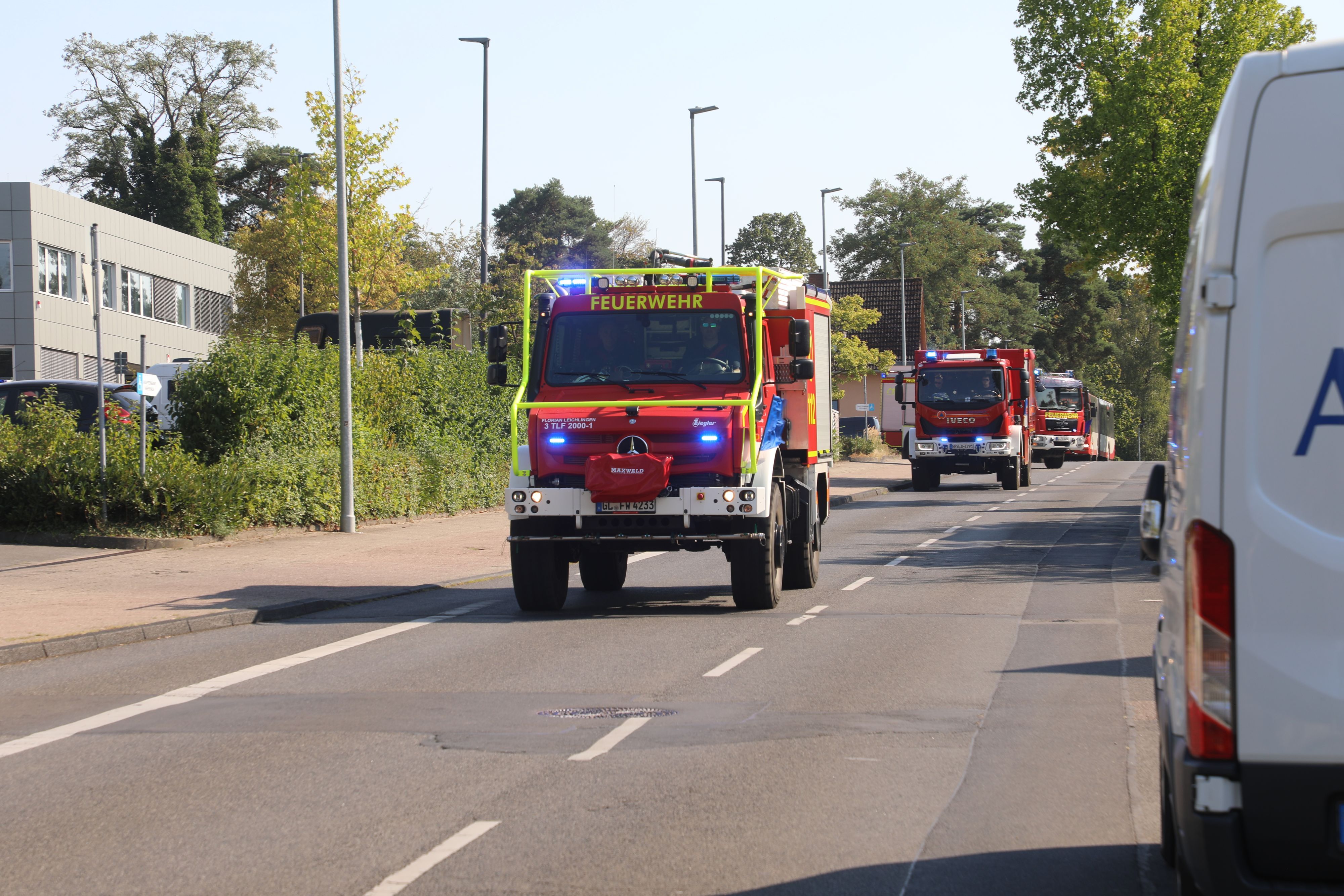 Feuerwehrfahrzeuge fahren mit Blaulicht und Martinshorn zum Waldbrandeinsatz bei Düren.