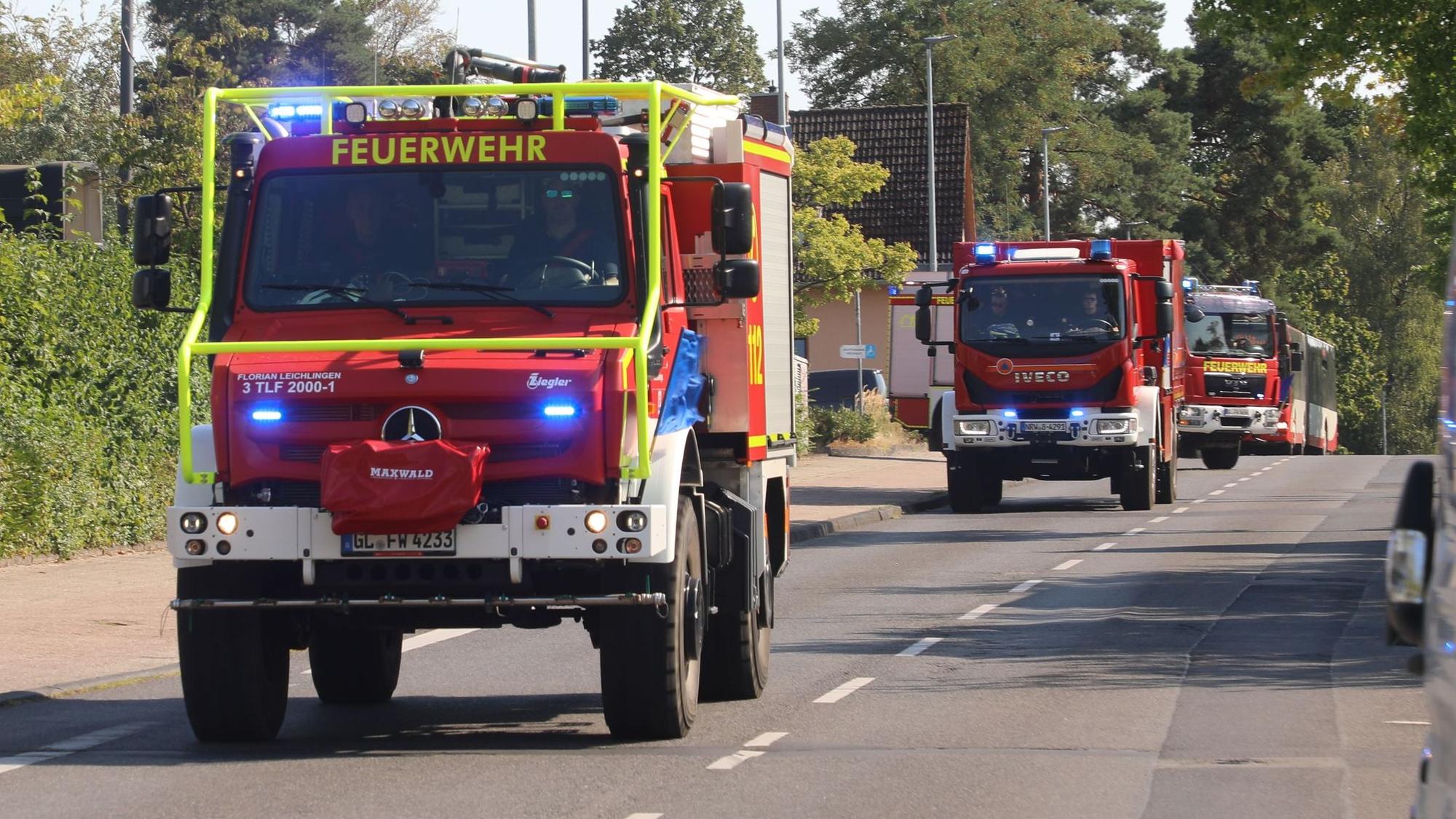 Feuerwehrfahrzeuge fahren mit Blaulicht und Martinshorn zum Waldbrandeinsatz bei Düren.