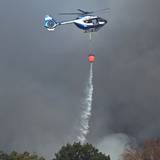 Ein Polizeihubschrauber mit Löschwasser-Außenlastbehälter unterstützt die Löscharbeiten beim Waldbrand im Hürtgenwald.