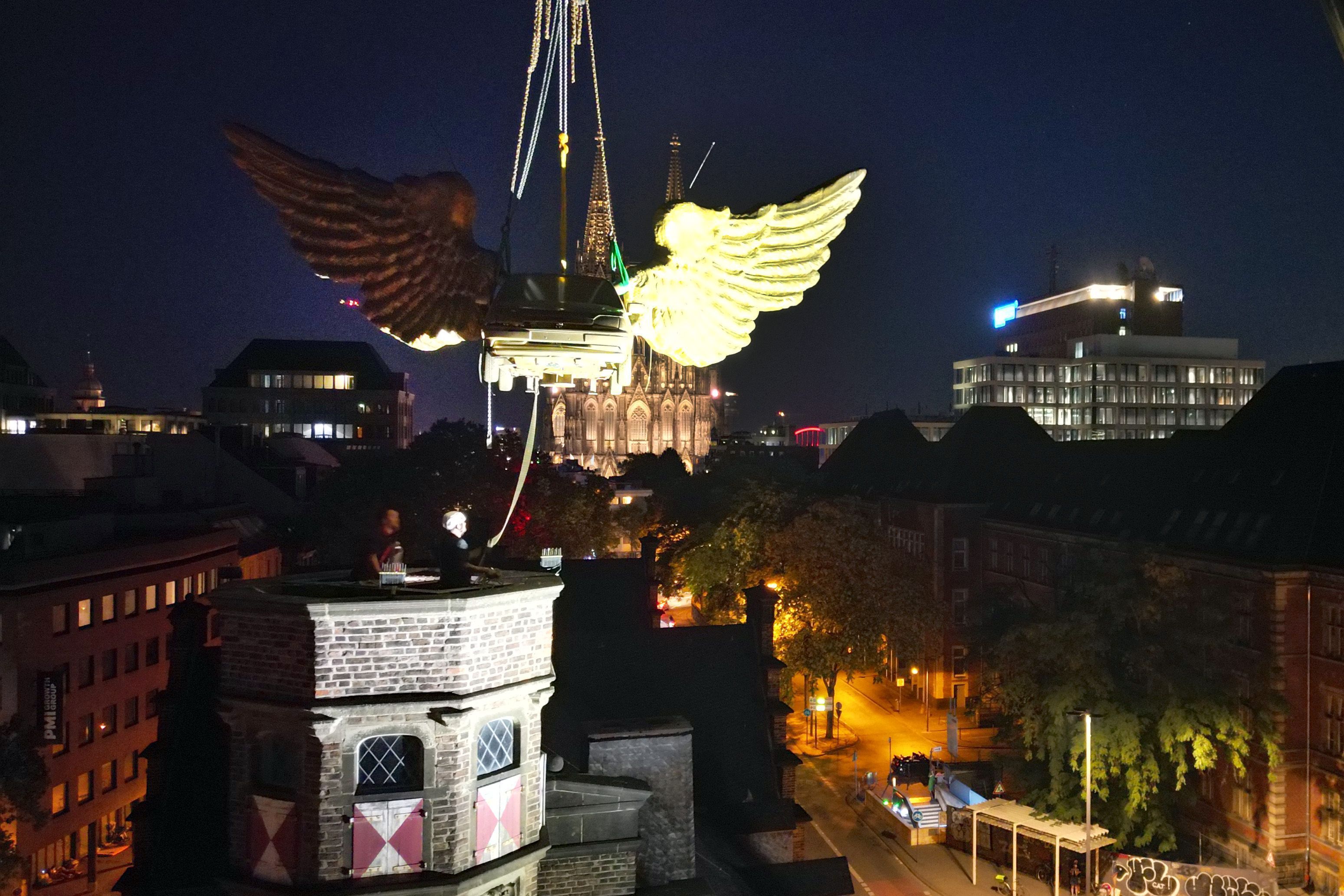 13.08.2026, Nordrhein-Westfalen, Köln: Das goldene Flügelauto des Kölner Künstlers HA Schult wird von einem Kran vom Turm des historischen Zeughauses gehoben, weil das Gebäude baufällig ist. Foto: Federico Gambarini/dpa +++ dpa-Bildfunk +++