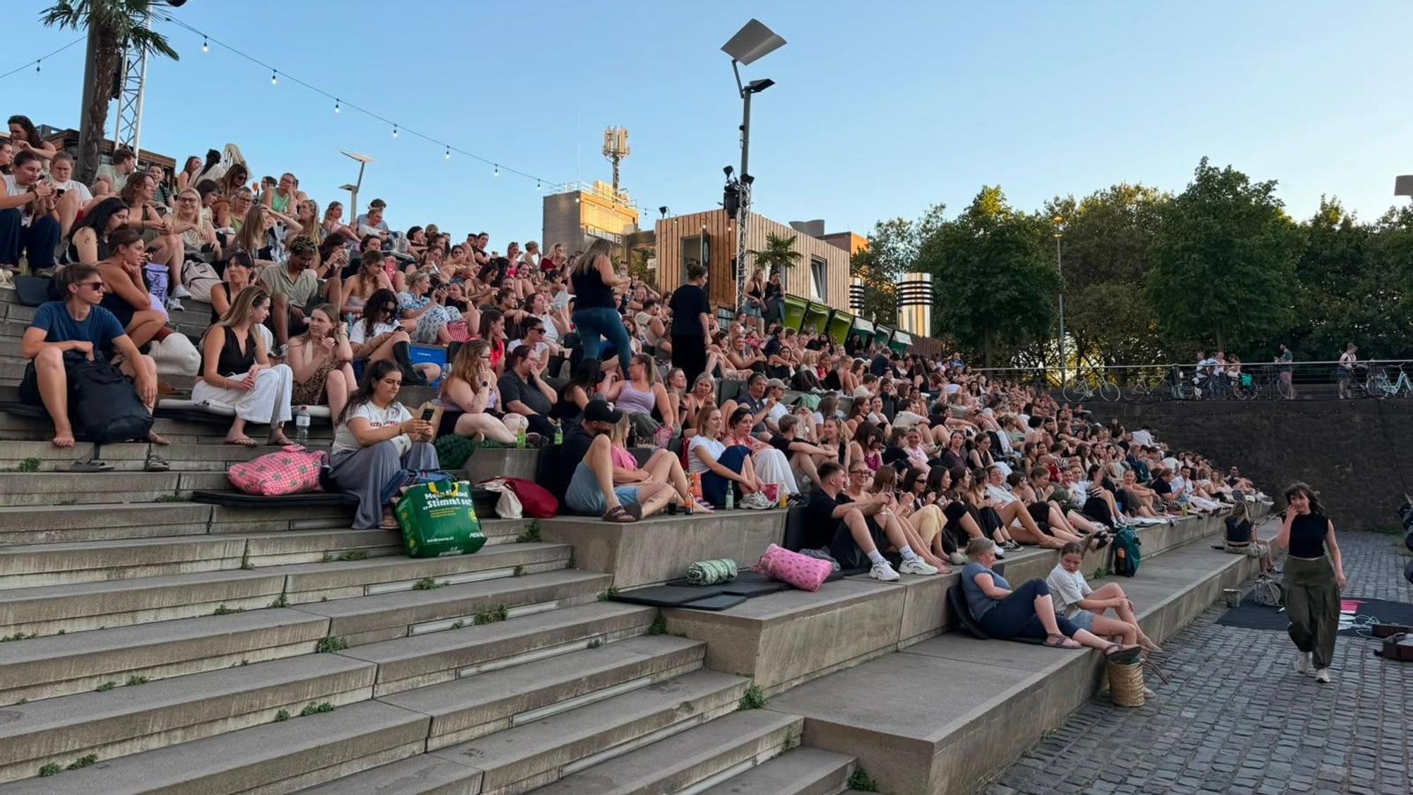 Menschen sitzen auf den Treppen im Kölner Rheinauhafen.