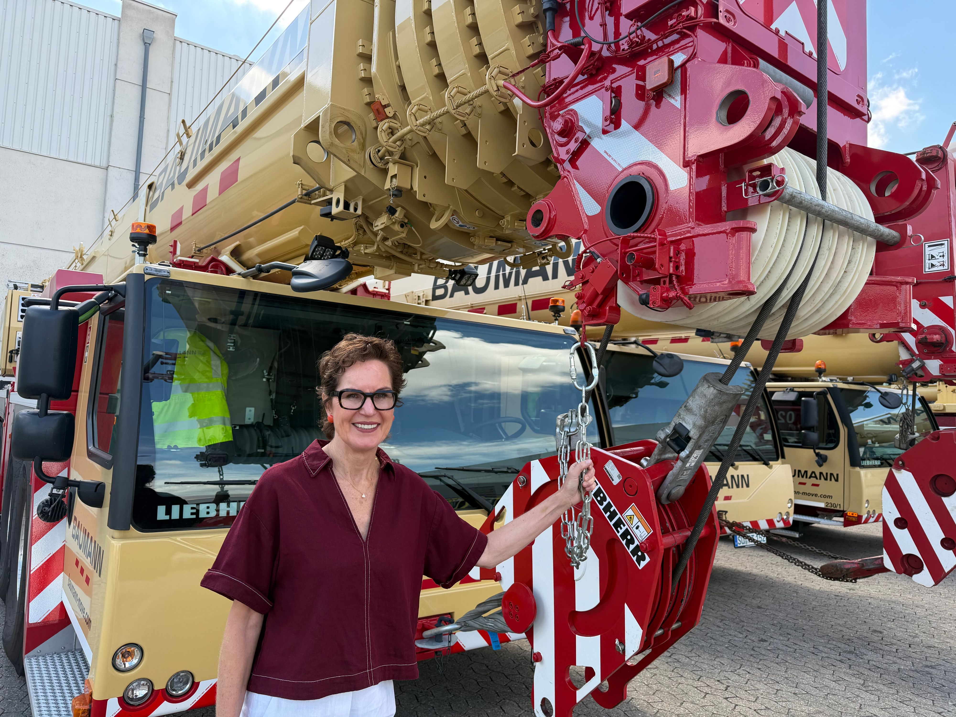 Sabine Baumann steht vor einem ihrer gewaltigen Liebherr Mobilkräne.