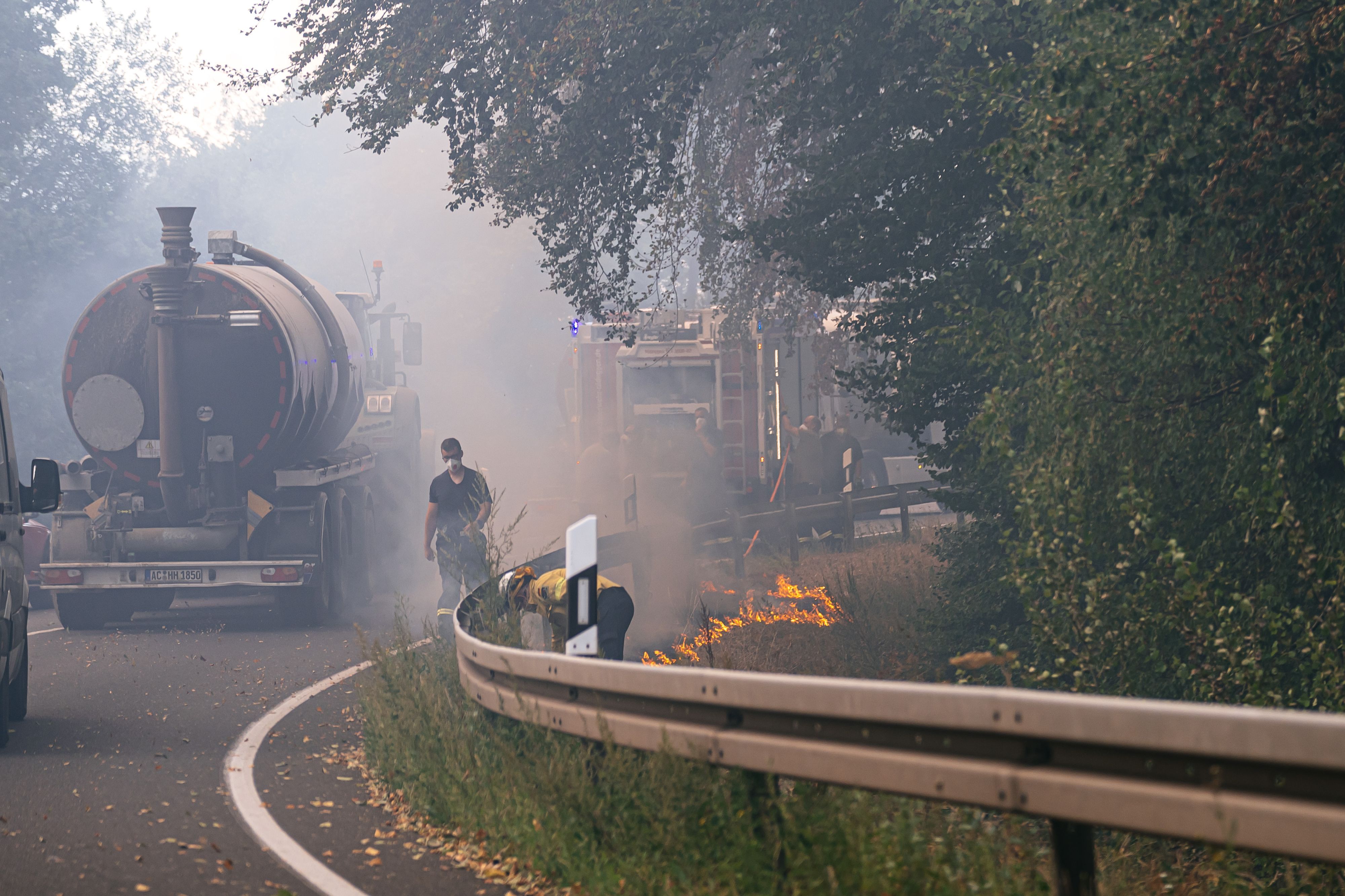 Waldbrand im Hürtgenwald. Am Straßenrand legen Einsatzkräfte ein sogenanntes Gegenfeuer und setzen Vegetation kontrolliert in Brand. So soll dem eigentlichen Feuer die Nahrung entzogen werden, wenn es die Stelle erreicht.