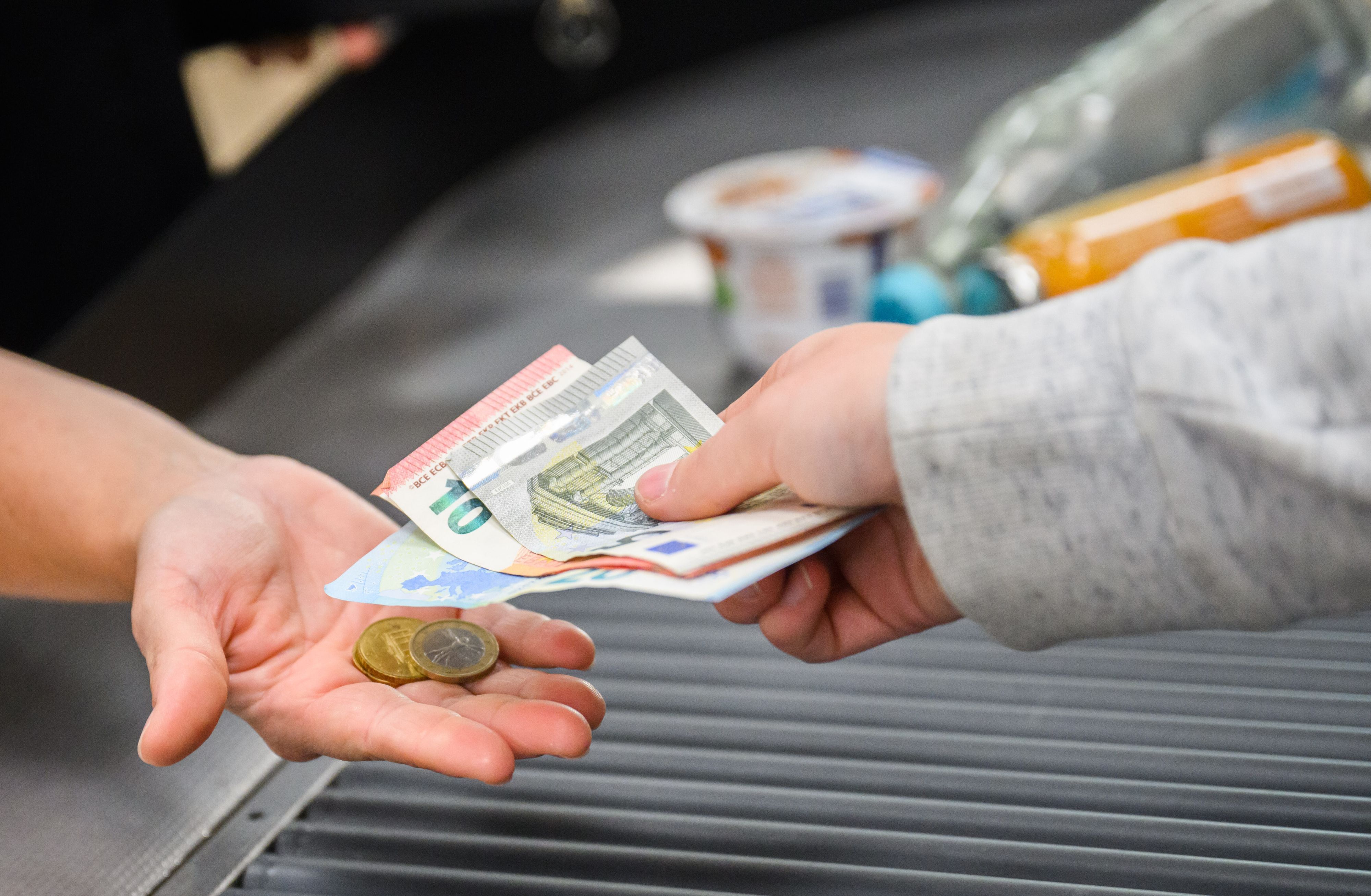 Eine Kassiererin gibt einer Kundin Wechselgeld an der Kasse eines Supermarktes.