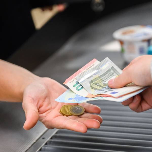 Eine Kassiererin gibt einer Kundin Wechselgeld an der Kasse eines Supermarktes.
