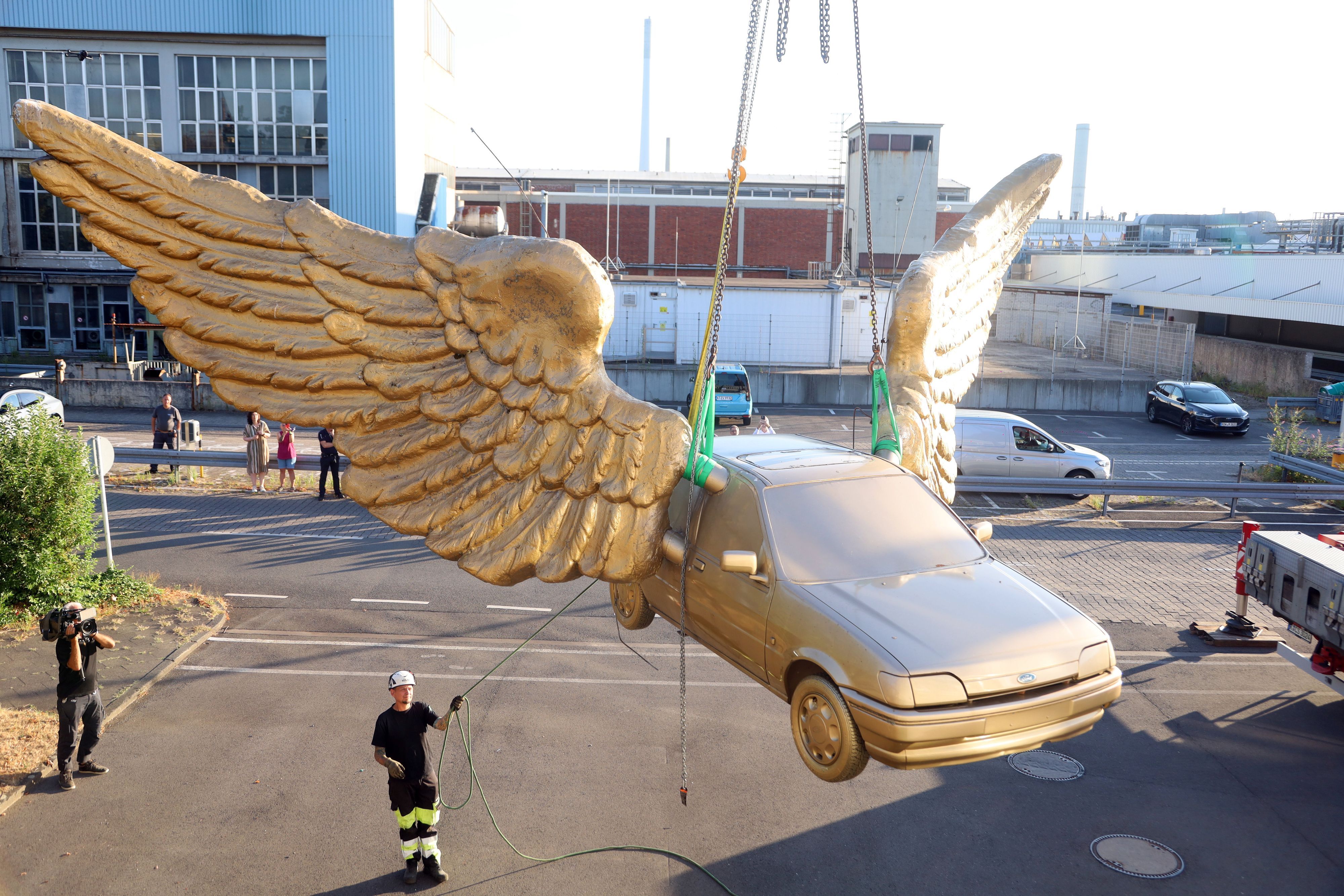 14.08.2026, Köln: Der „Goldene Vogel“, eine meist nur als  „Flügelauto“ bezeichnete Skulptur des Künstlers HA Schult, wird von seinem Platz auf dem Treppenturm des historischen Zeughauses entfernt. Dort war es seit 1991 platziert. Nach einer Restauration bei Ford soll es an anderer Stelle wieder aufgestellt werden. Foto: Arton Krasniqi