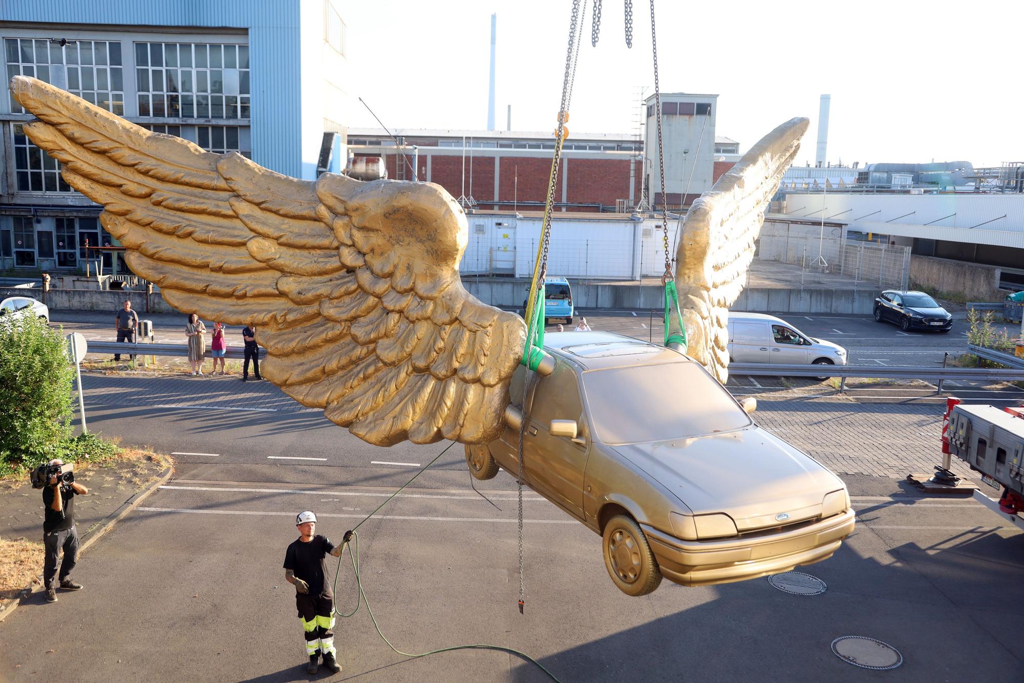 14.08.2026, Köln: Der „Goldene Vogel“, eine meist nur als „Flügelauto“ bezeichnete Skulptur des Künstlers HA Schult, wird von seinem Platz auf dem Treppenturm des historischen Zeughauses entfernt. Dort war es seit 1991 platziert. Nach einer Restauration bei Ford soll es an anderer Stelle wieder aufgestellt werden. Foto: Arton Krasniqi