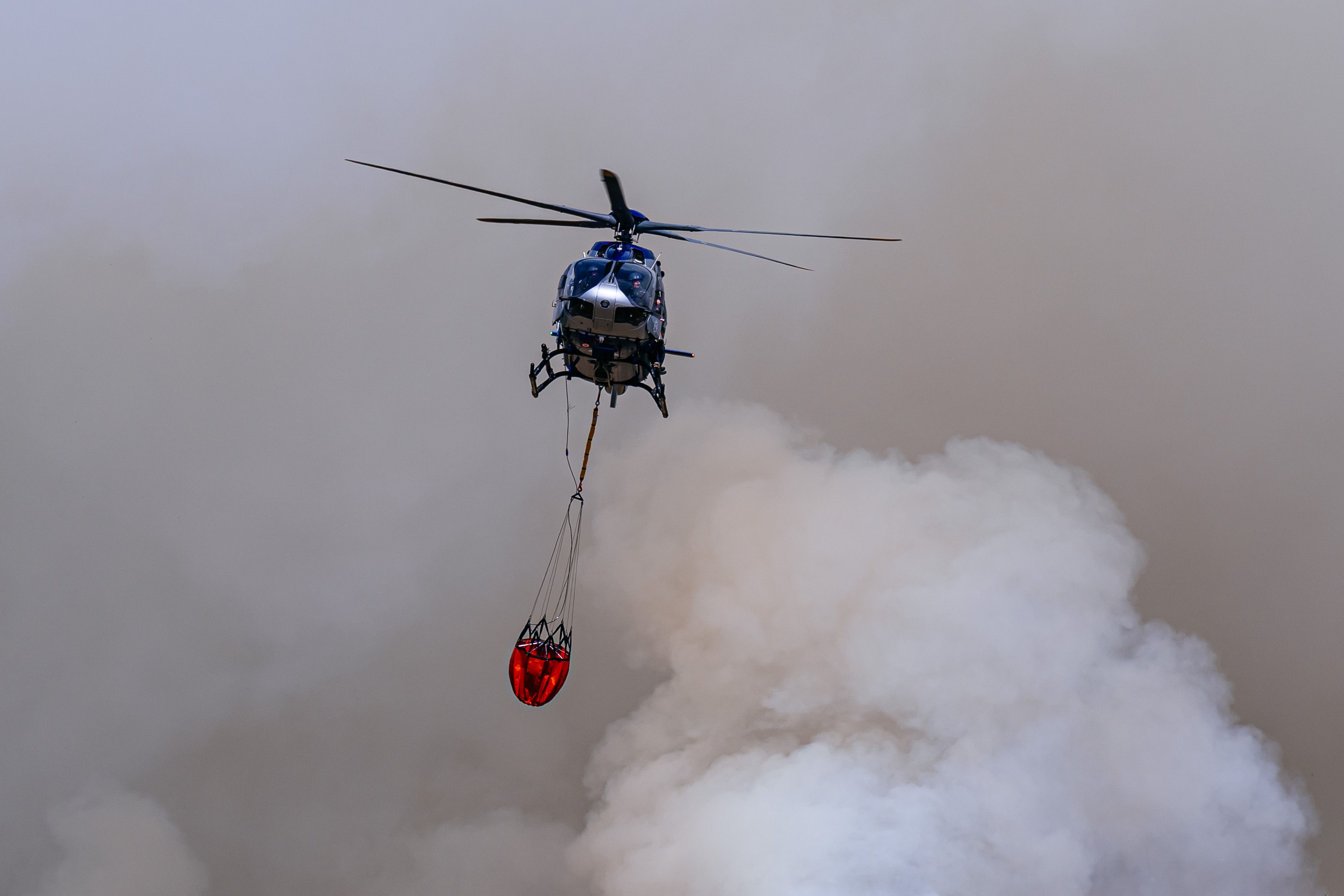 An einer Einsatzstelle werden Hubschrauber mit Löschwasser befüllt. Das Wasser wird anschließend zur Brandbekämpfung aus der Luft eingesetzt.