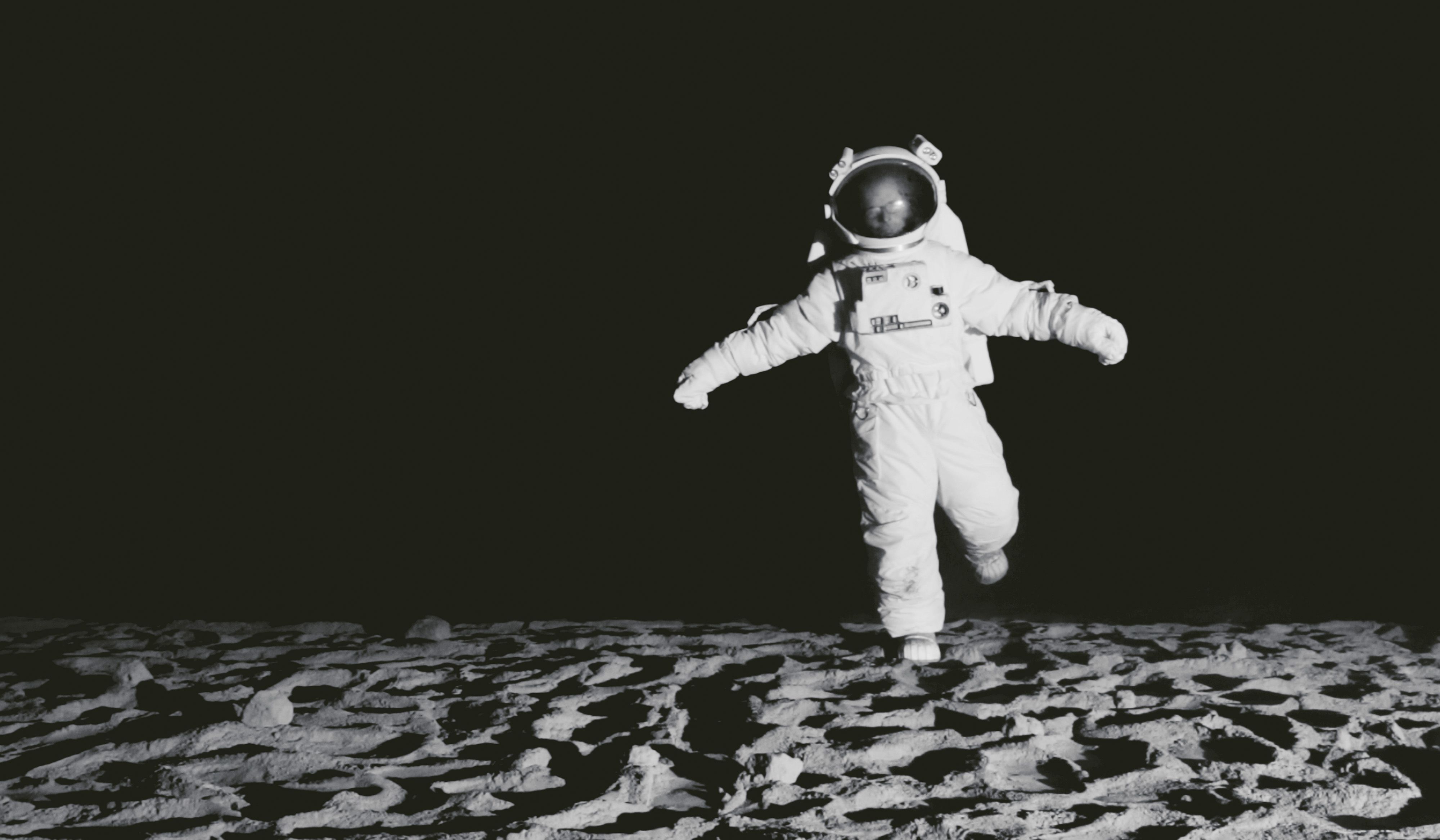 Ein Astronaut steht gelangweilt auf dem Mond.