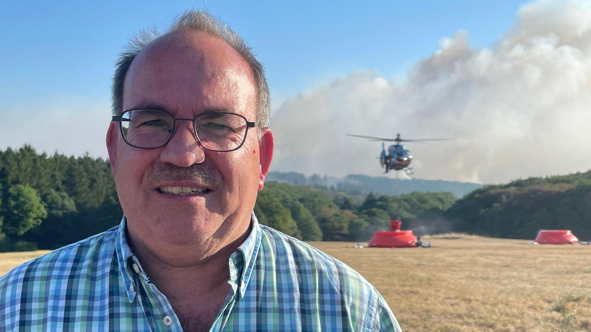 Ralf Nolten (CDU), Landrat vom Kreis Düren, spricht unweit des Waldbrands im Hürtgenwald.