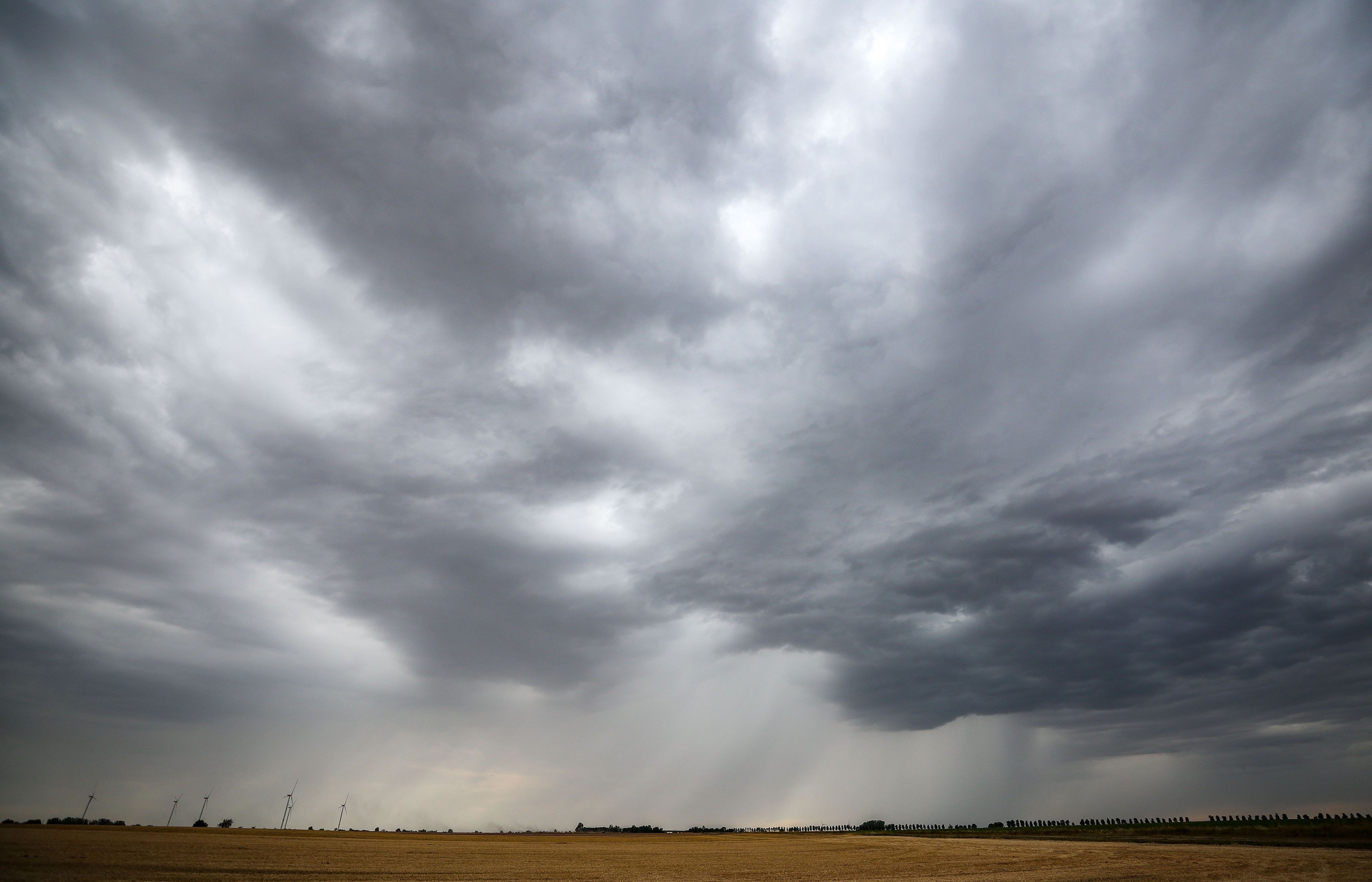 Eine Regenfront zieht über ein Getreidefeld hinweg. In Nordrhein-Westfalen soll es ab dem Sonntag kühler werden. (Archivbild)