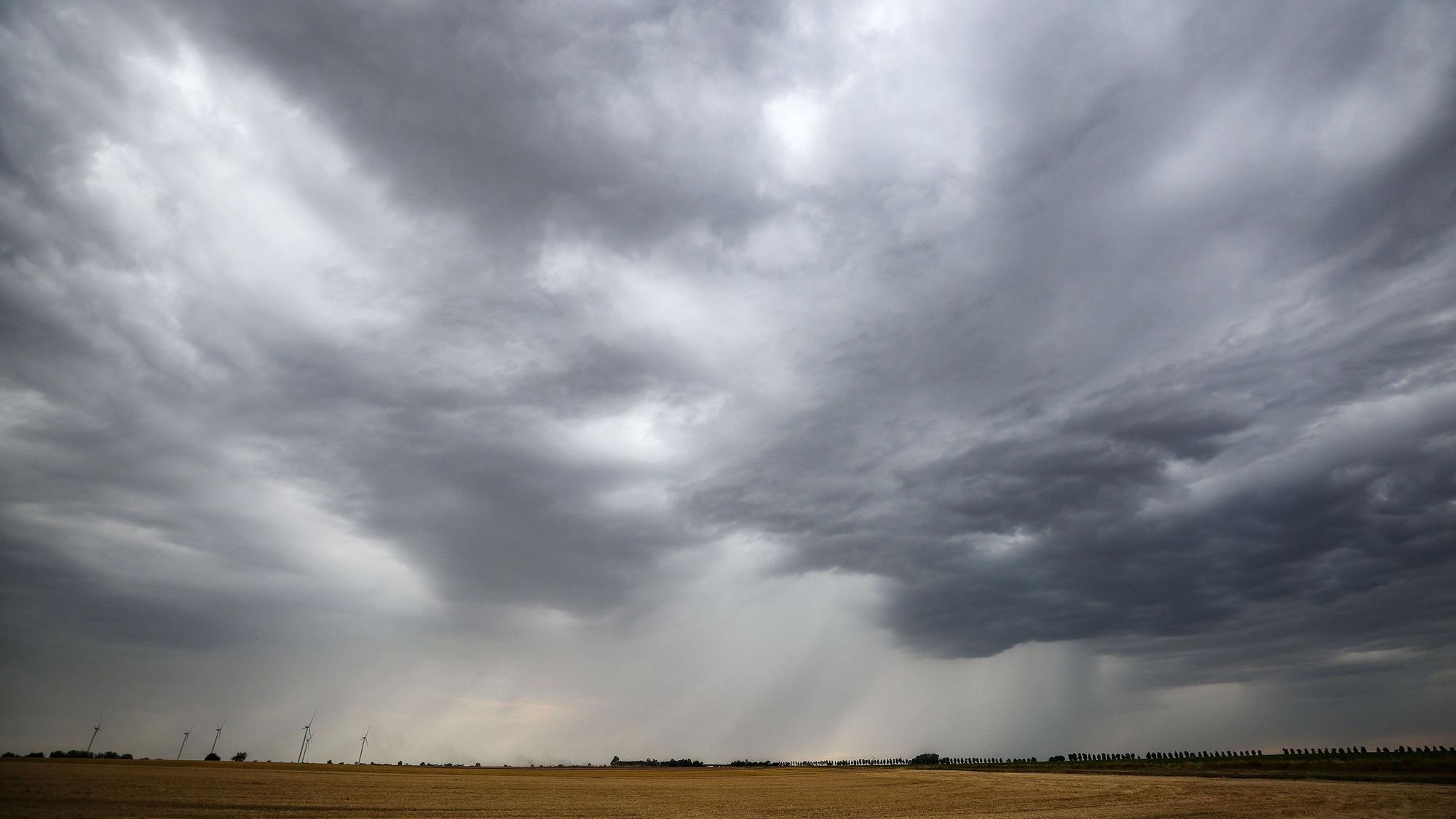 Eine Regenfront zieht über ein Getreidefeld hinweg. In Nordrhein-Westfalen soll es ab dem Sonntag kühler werden. (Archivbild)