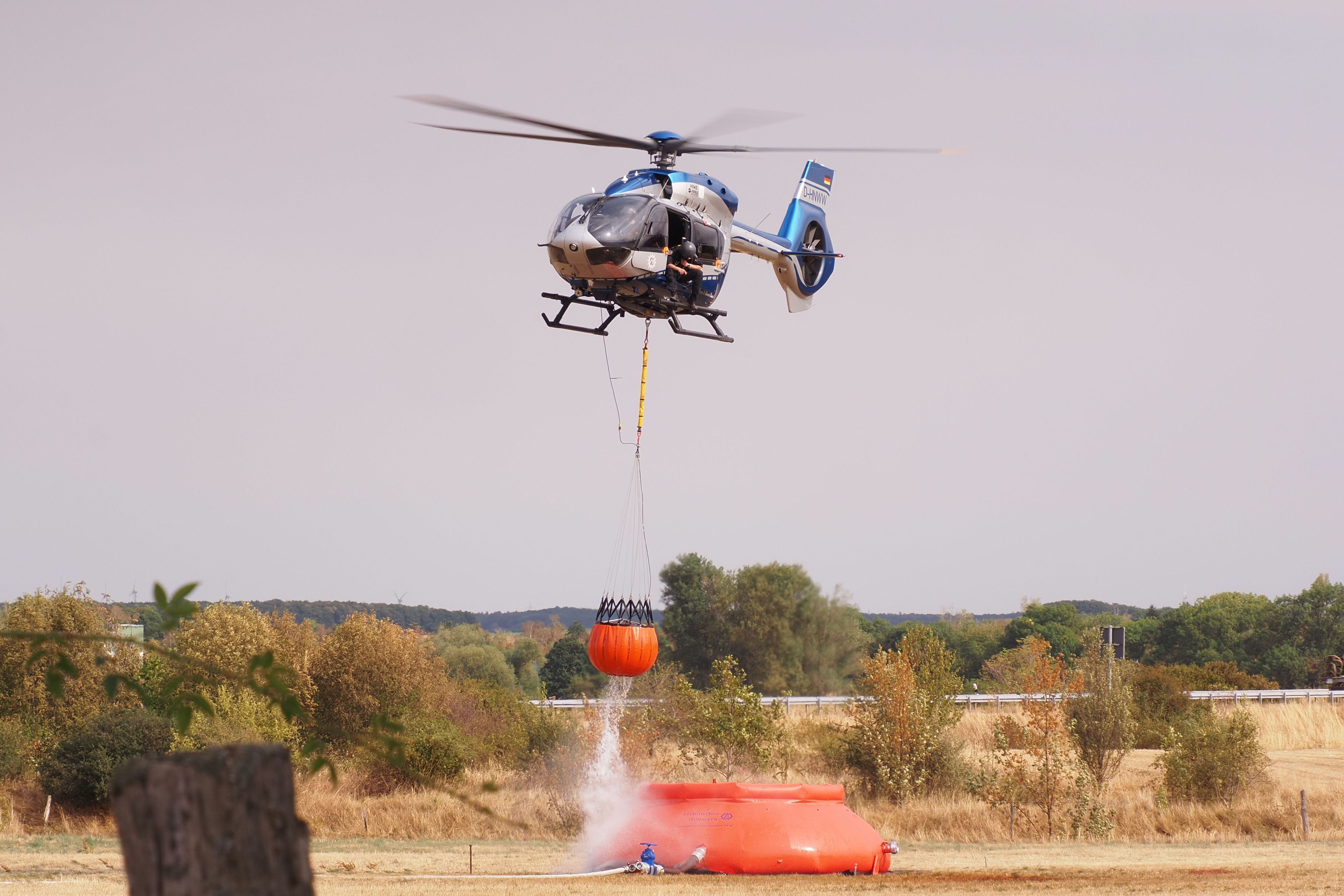 Ein Hubschrauber nimmt nahe der Ortschaft Gey Löschwasser auf.