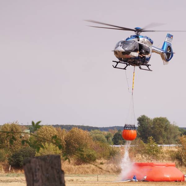 Ein Hubschrauber nimmt nahe der Ortschaft Gey Löschwasser auf.