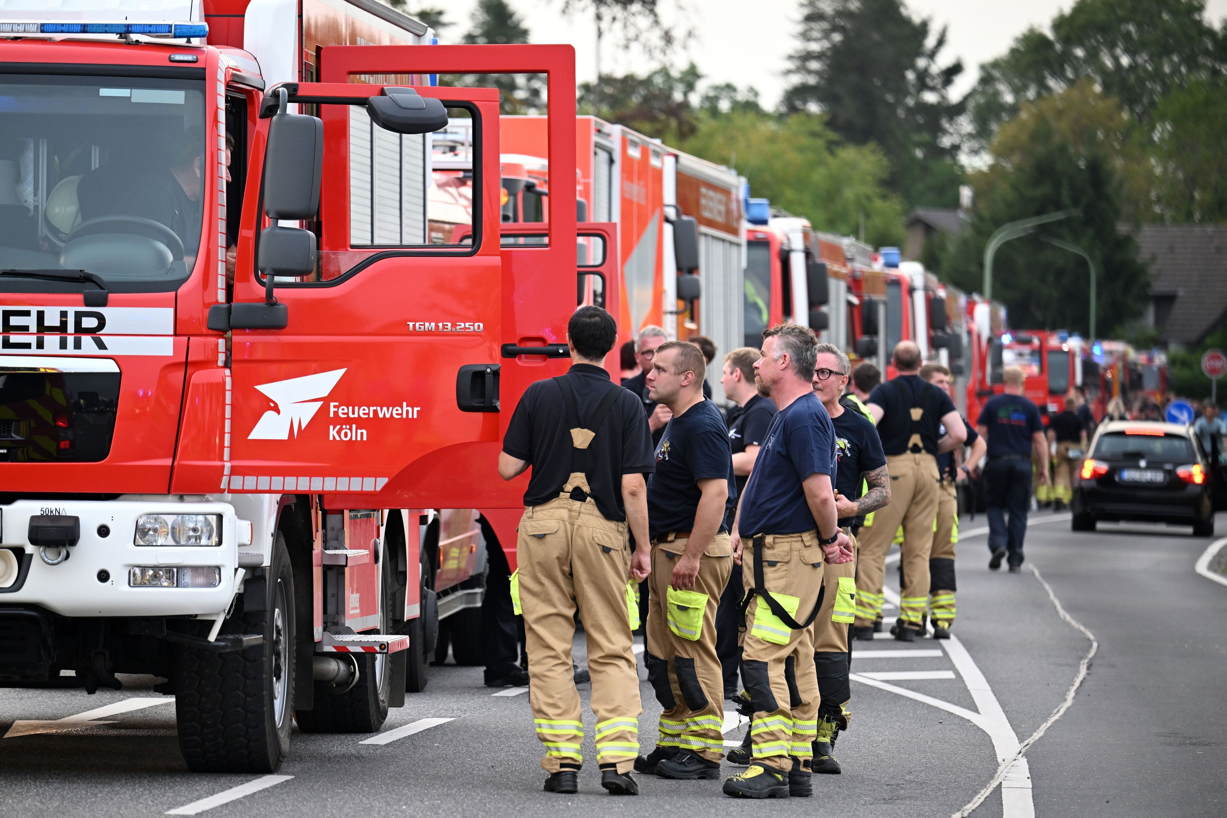 Zahlreiche Kräfte der Feuerwehr stehen an einer Straße. Sie sollen als Ablösung die Löscharbeit beim Waldbrand im Hürtgenwald übernehmen. Den Waldbrand haben die Einsatzkräfte unter Kontrolle gebracht.