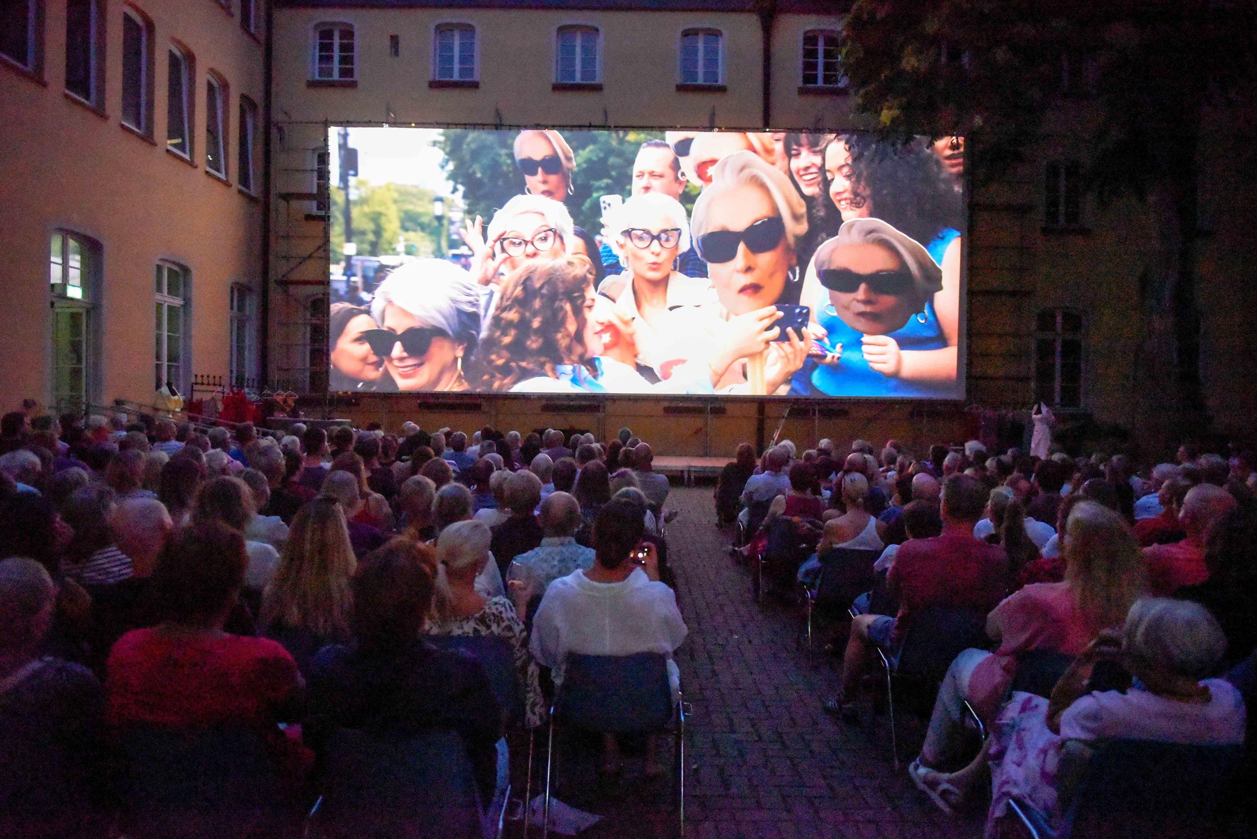 Rund 440 Zuschauer verfolgen unter freiem Himmel einen Film auf einer großen Leinwand.