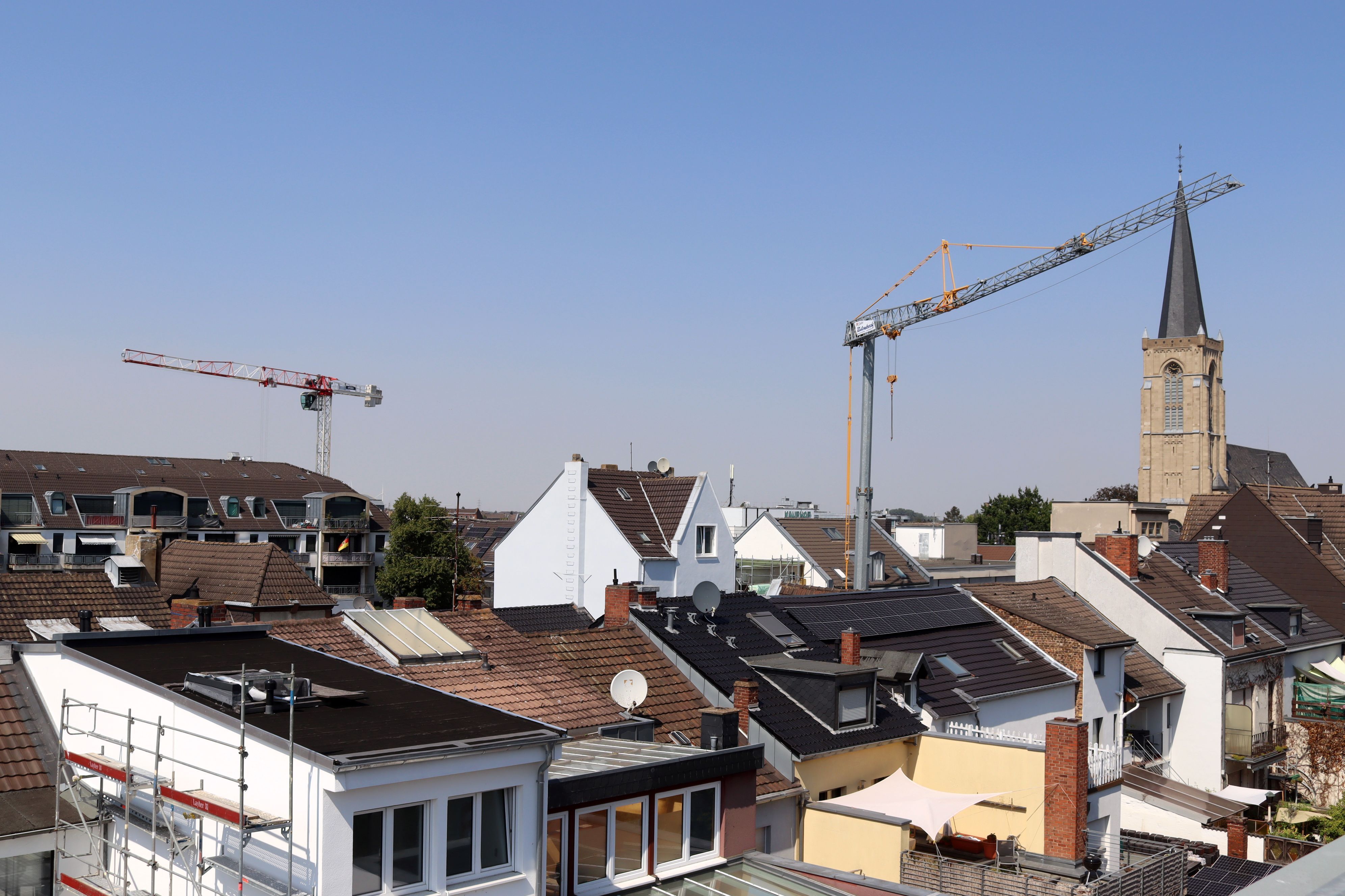 Über den Dächern der Stadt Euskirchen erheben sich zwei Baukräne, rechts ist die Herz-Jesu-Kirche zu sehen.