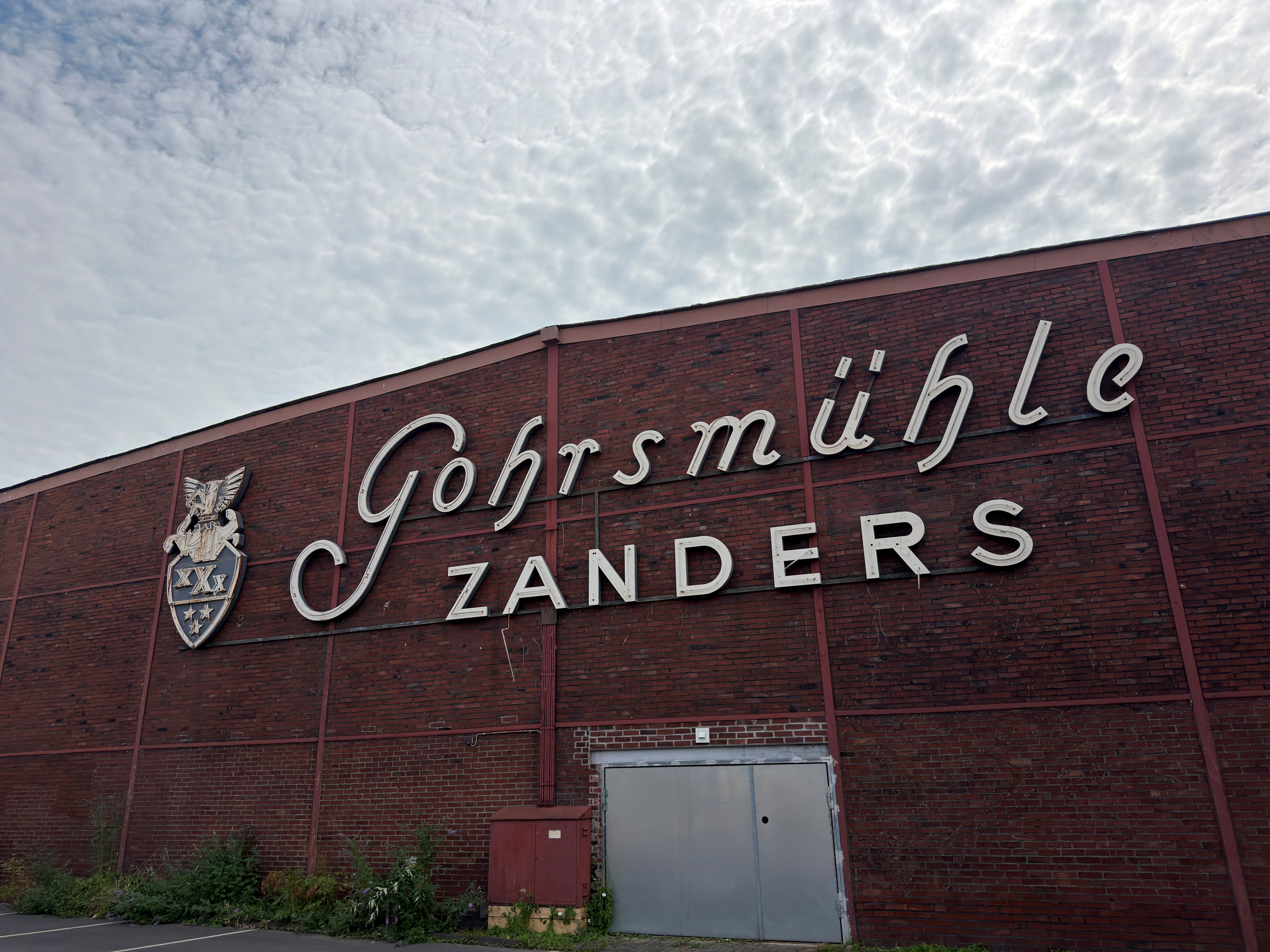 An einer Zanders-Halle hängt ein zerstörter Schriftzug.
