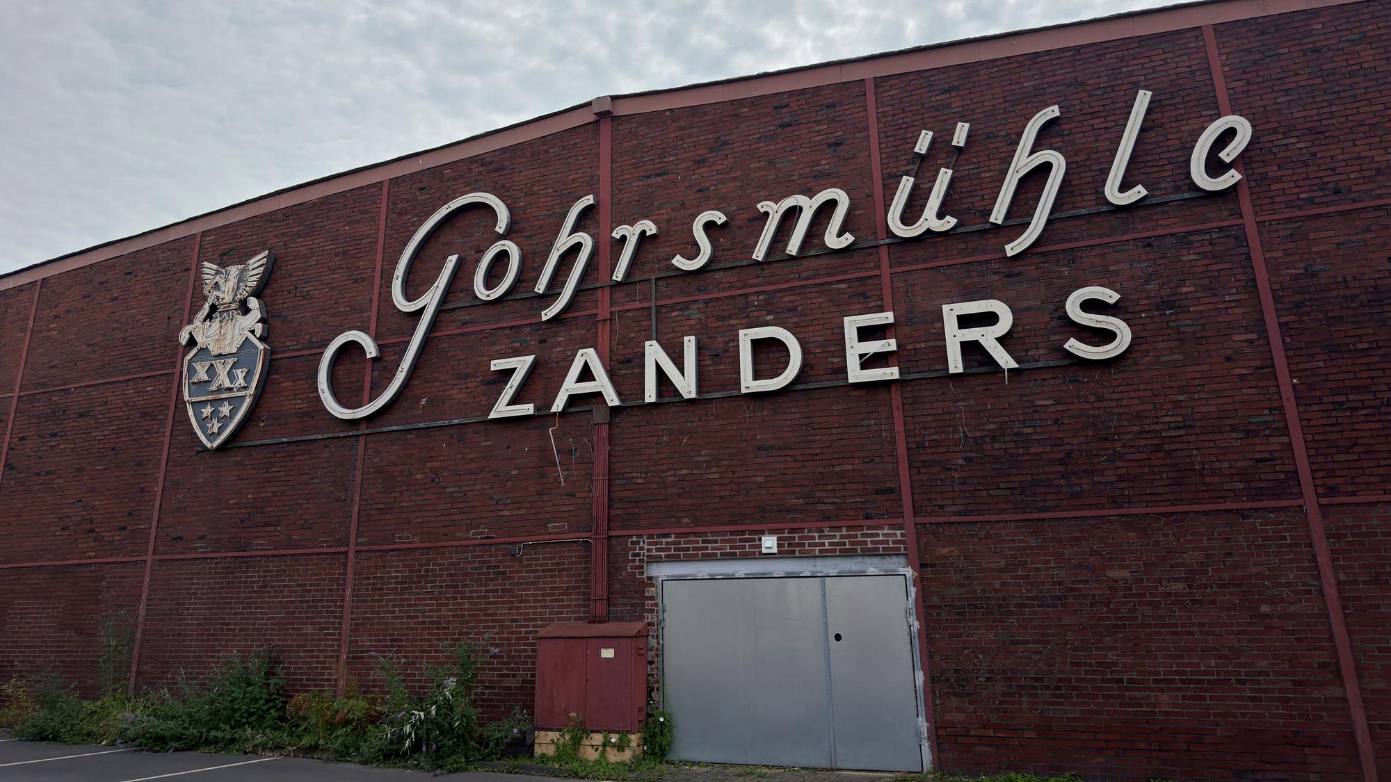 An einer Zanders-Halle hängt ein zerstörter Schriftzug.