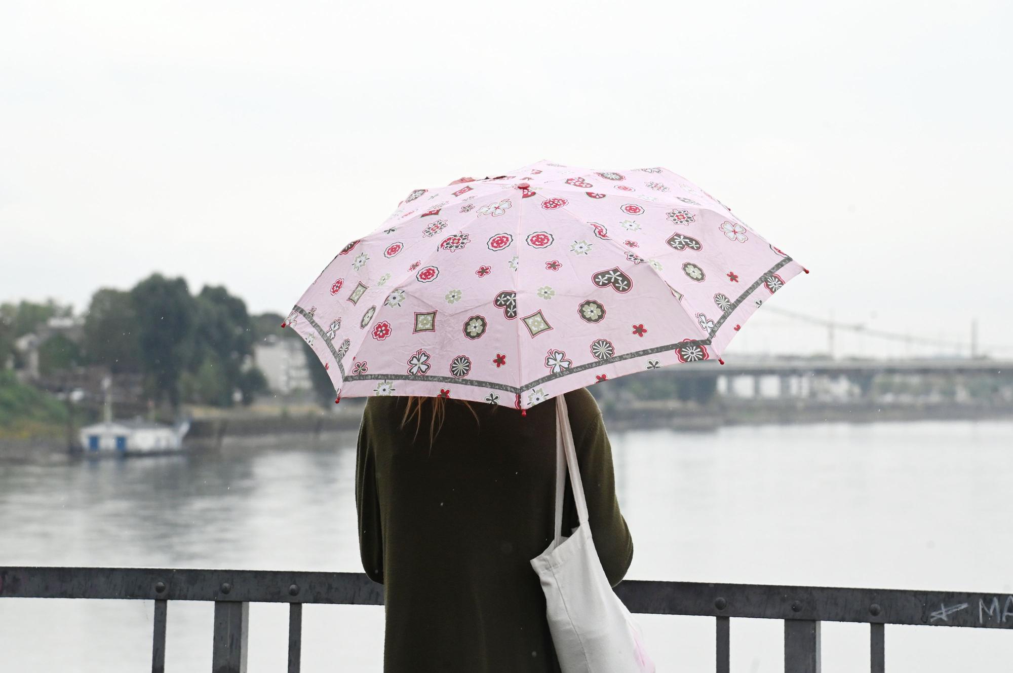Endlich Regen: Eine Frau mit Regenschirm am Rheinufer in Mülheim.