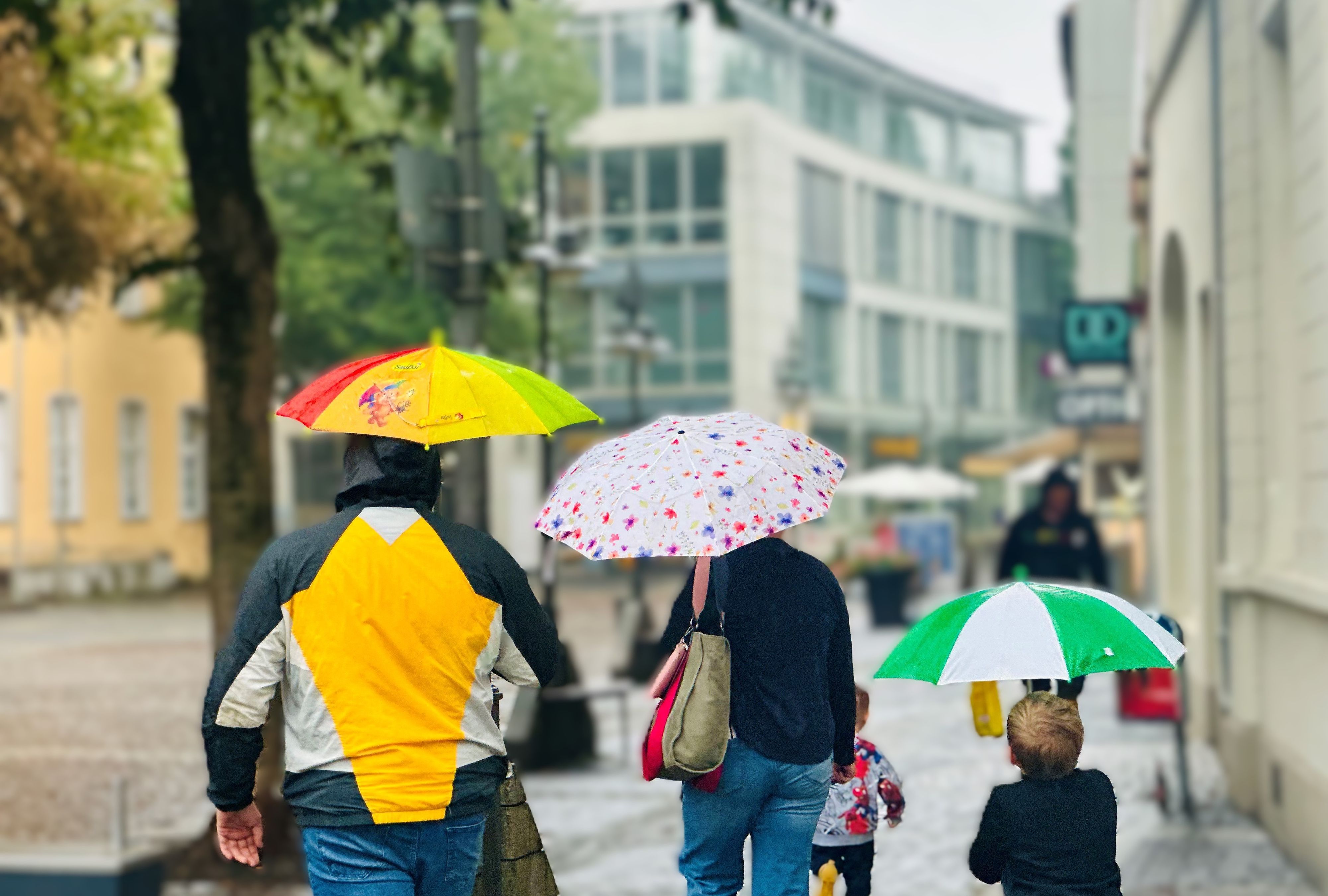 Menschen mit Regenschirmen gehen durch die Innenstadt von Brühl.