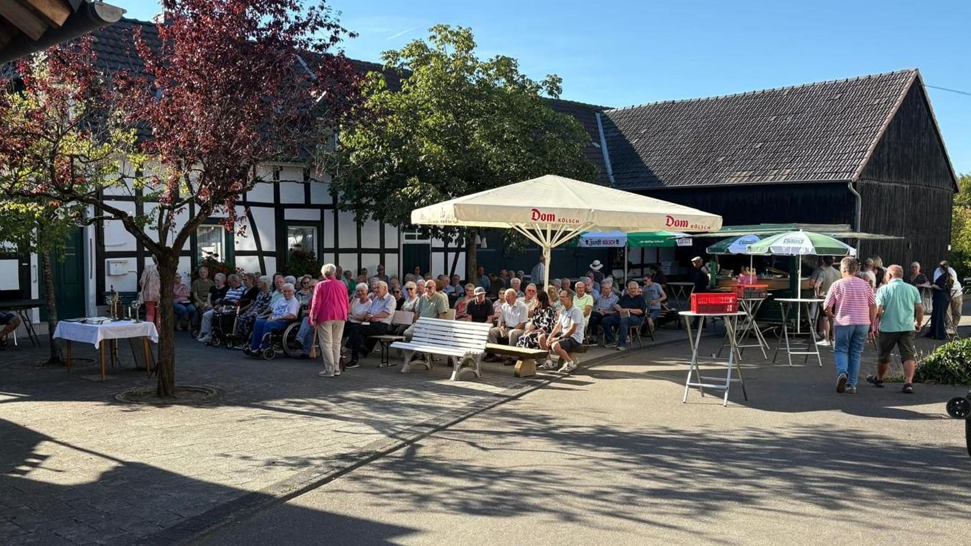Menschen sitzen im Weiler Cyriax.