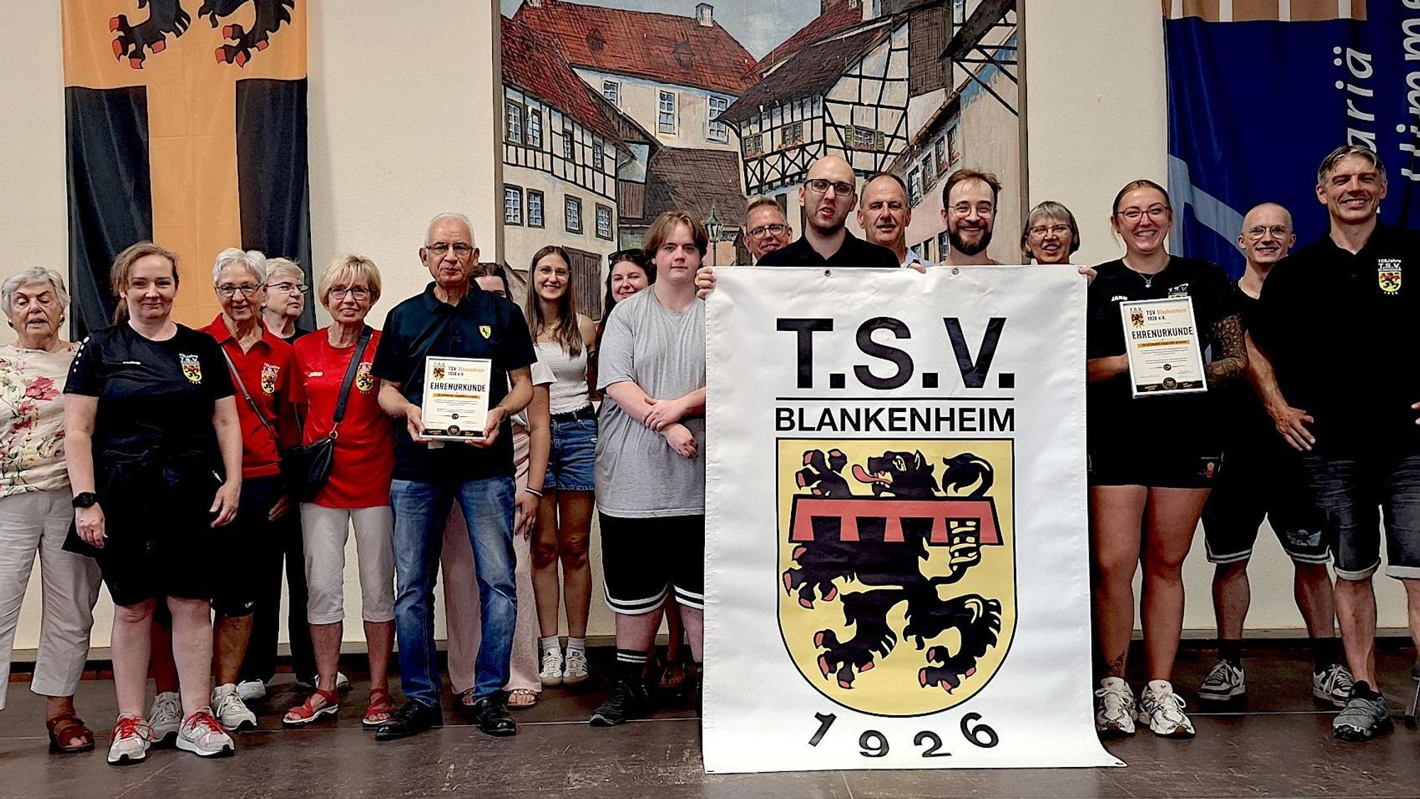 Einige Mitglieder haben sich zum Gruppenfoto postiert und halten des Vereins banner.