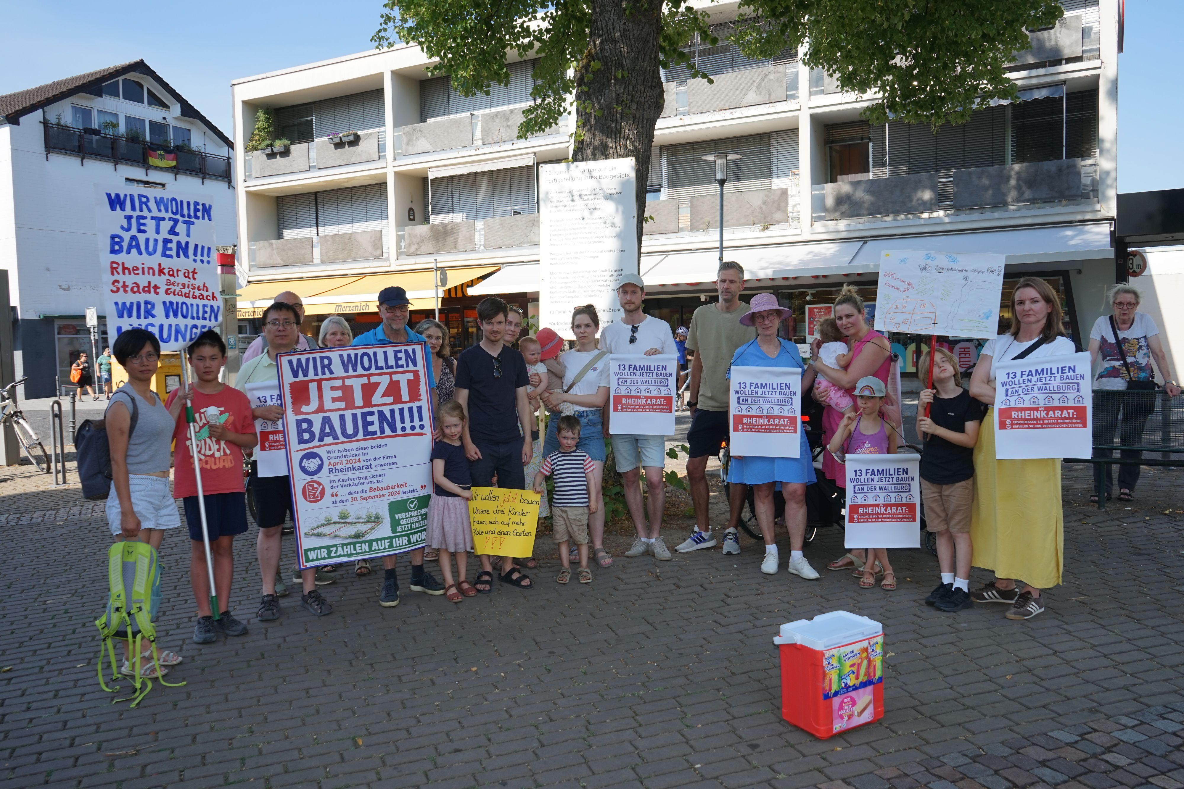 Menschen im Halbrund mit Protestplakaten, Aufschrift "Wir wollen jetzt bauen"
