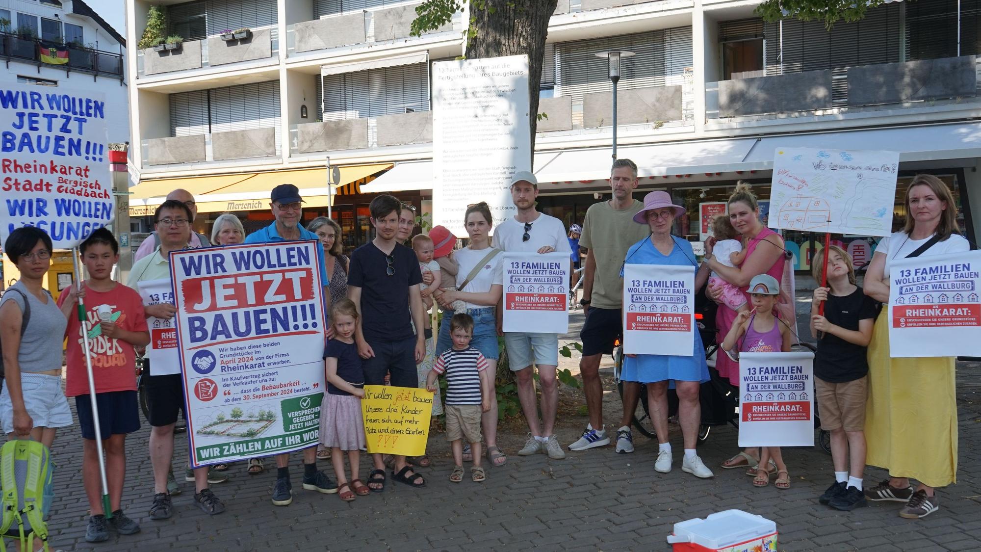 Menschen im Halbrund mit Protestplakaten, Aufschrift "Wir wollen jetzt bauen"