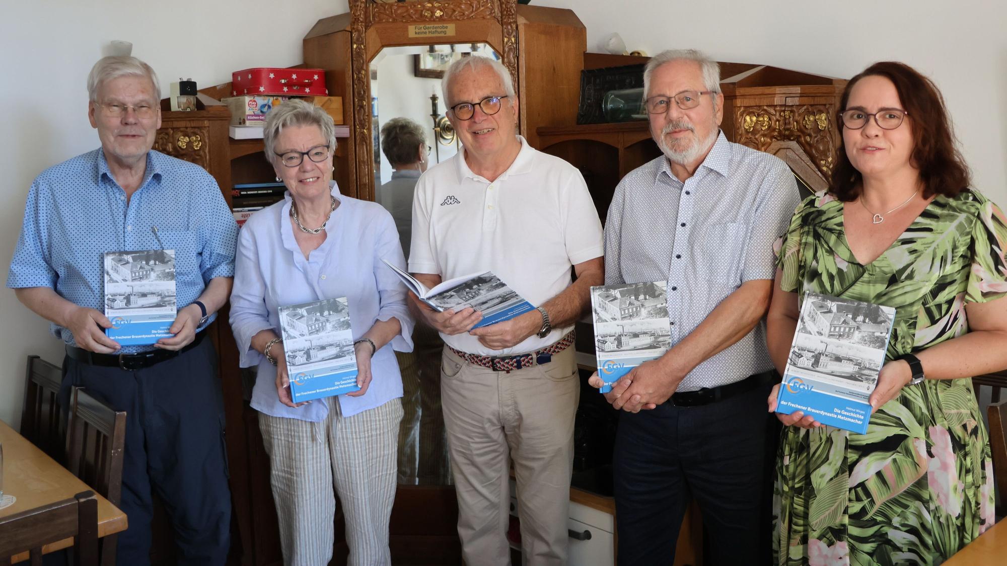 Auf dem Bild ist eine Gruppe von Frauen und Männer zu sehen, die ein Buch in die Kamera halten.