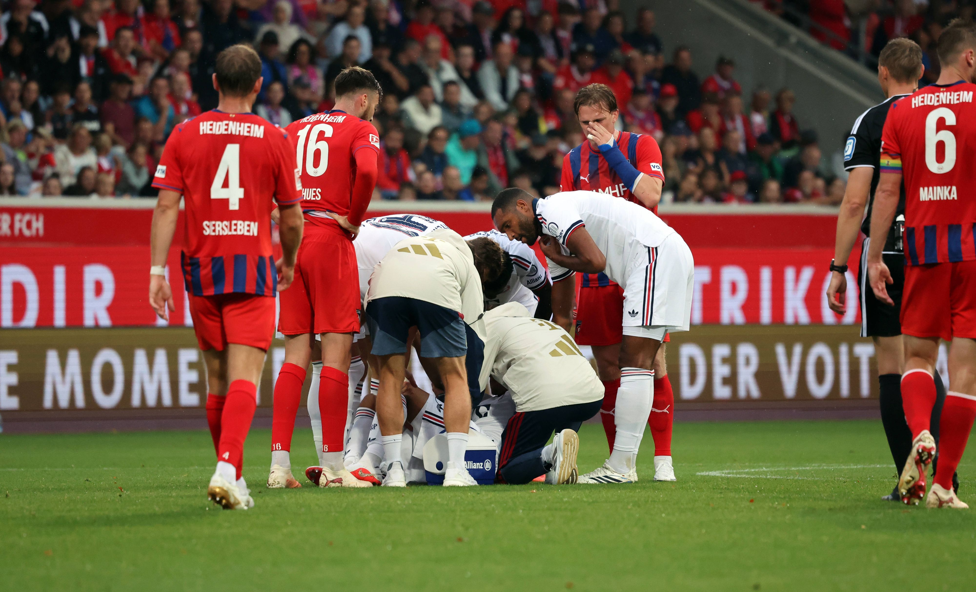 Betreuer und Spieler kümmern sich um Jamal Musiala, der am Boden liegt.
