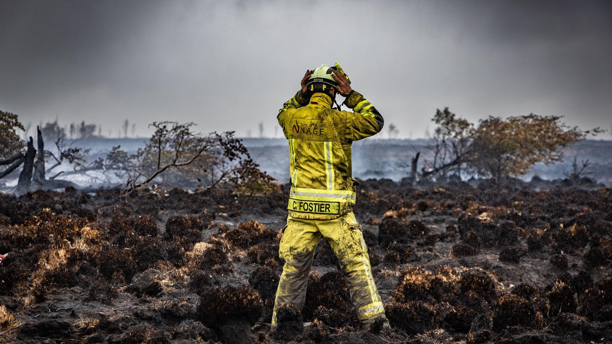 Ein Feuerwehrmann steht am Brandort im Naturschutzgebiet Hohes Venn.