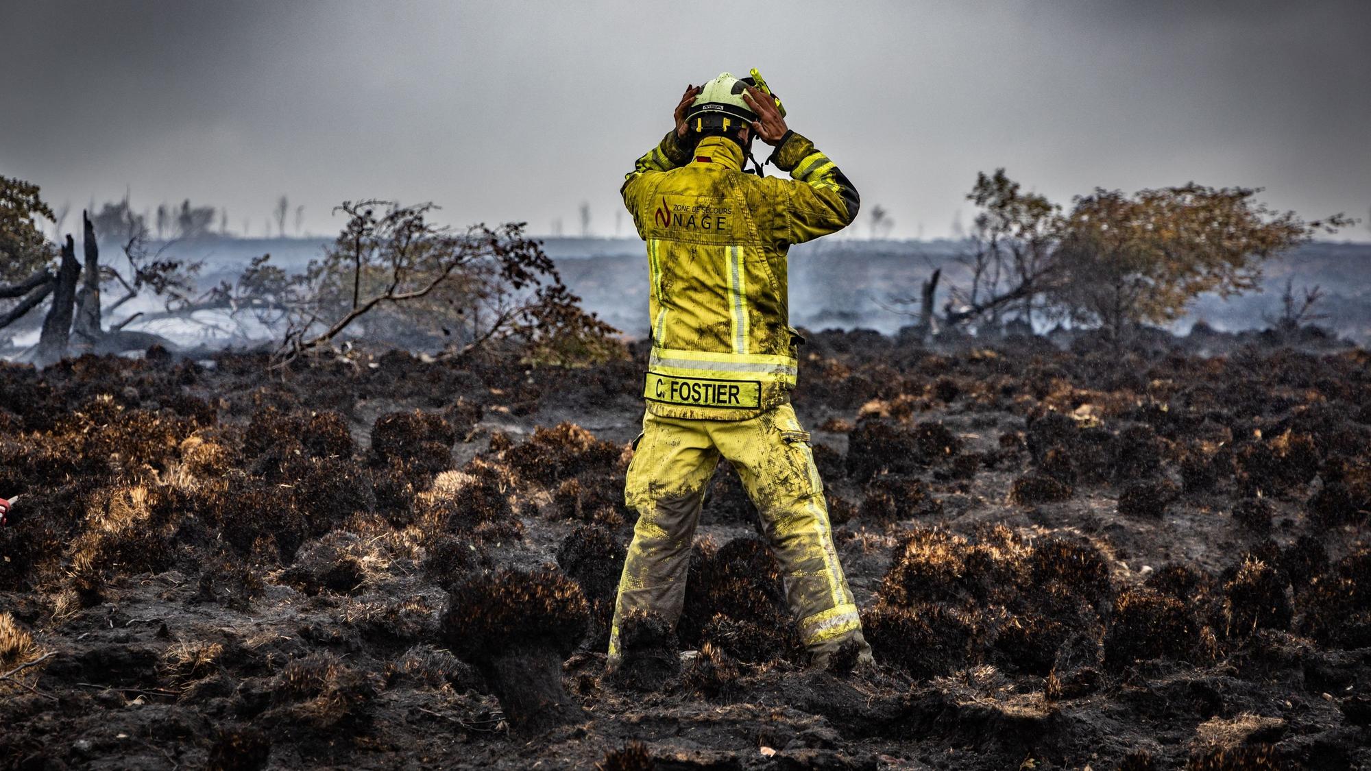 Ein Feuerwehrmann steht am Brandort im Naturschutzgebiet Hohes Venn.